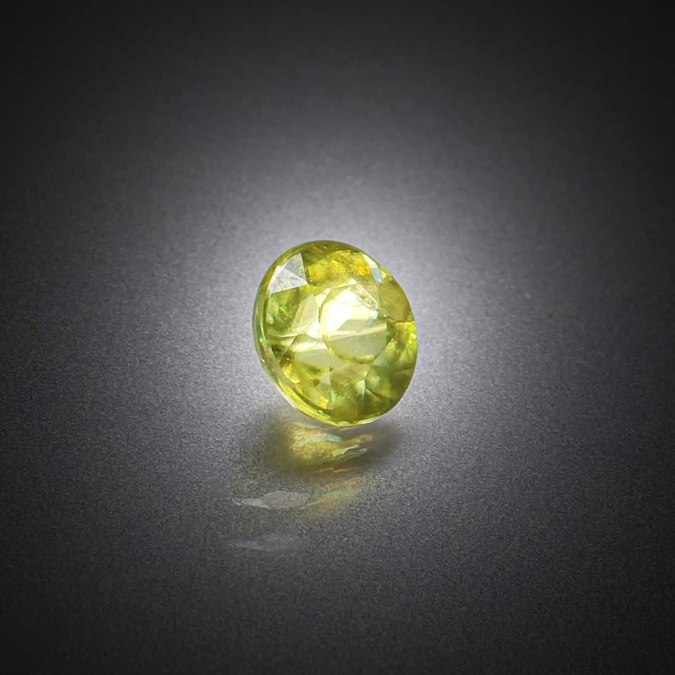 Sphène (titanite) jaune rond sur papier. - Lazuli