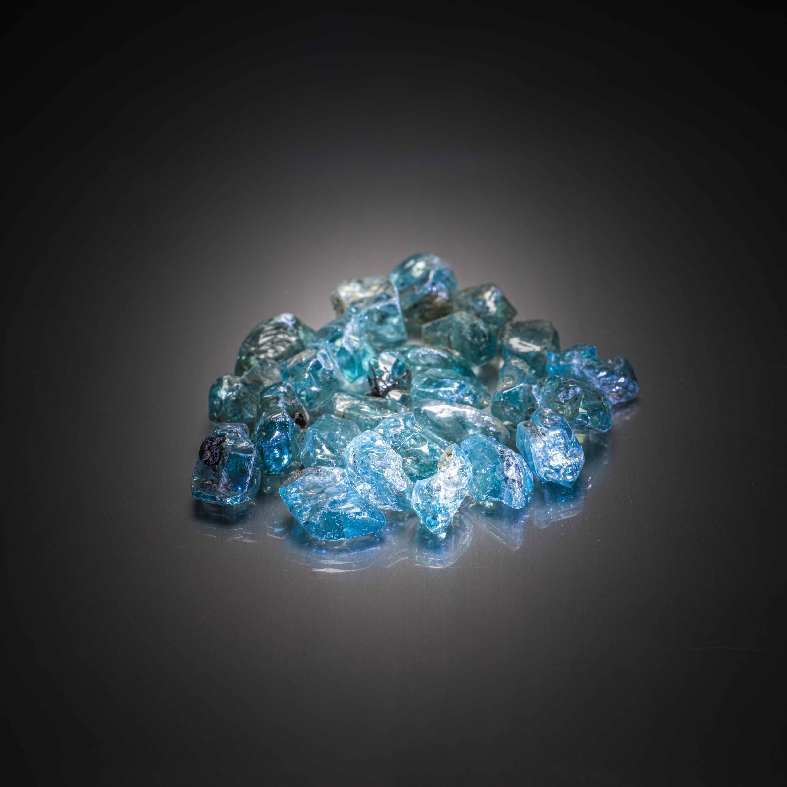 Lot de zircons bleus bruts sur papier. - Lazuli