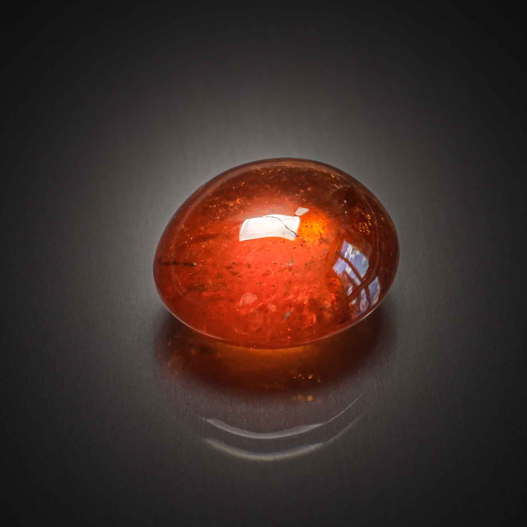 Grenat orange spessartite ovale cabochon sur papier. - Lazuli