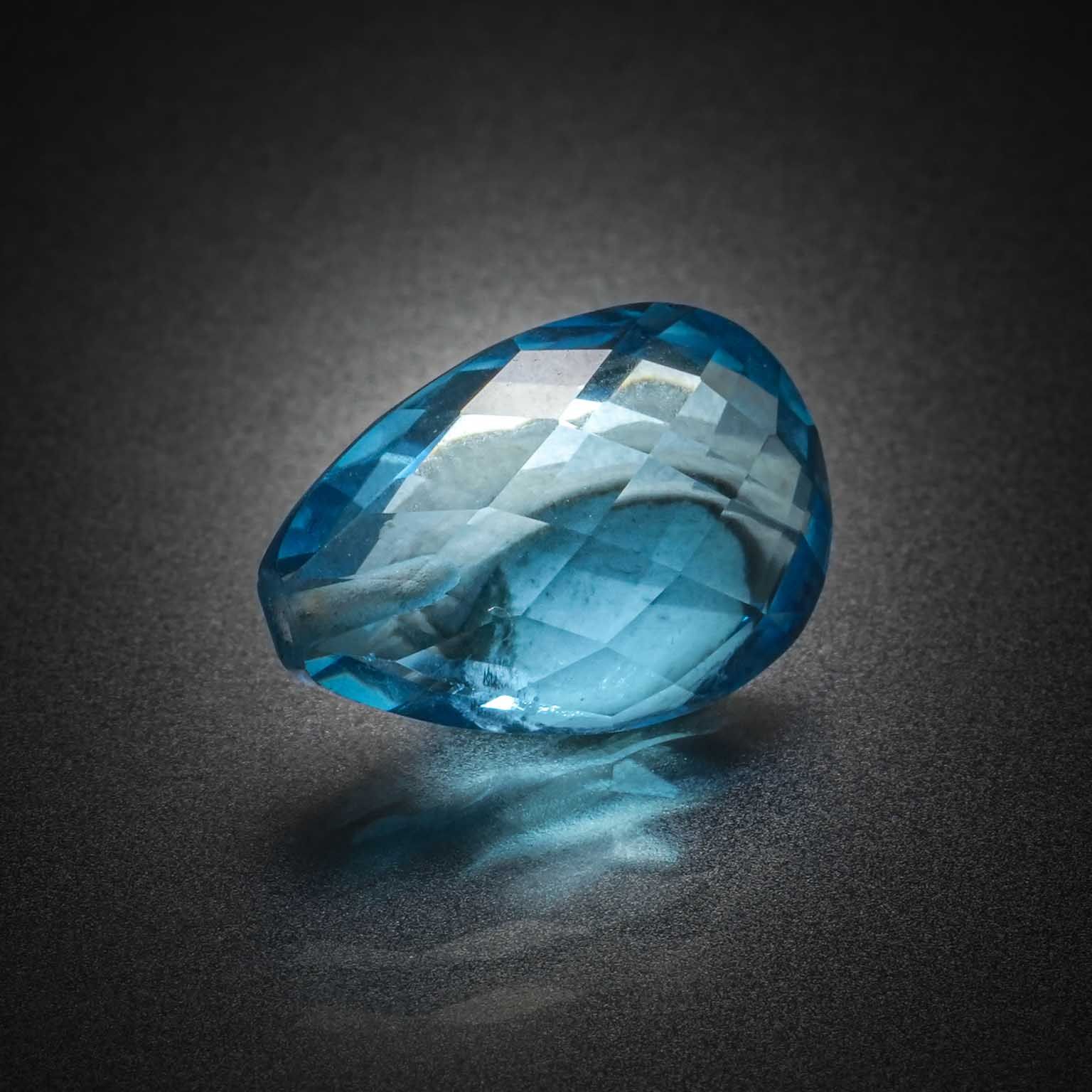 Topaze bleue (Swiss Blue) briolette sur papier (percée). - Lazuli