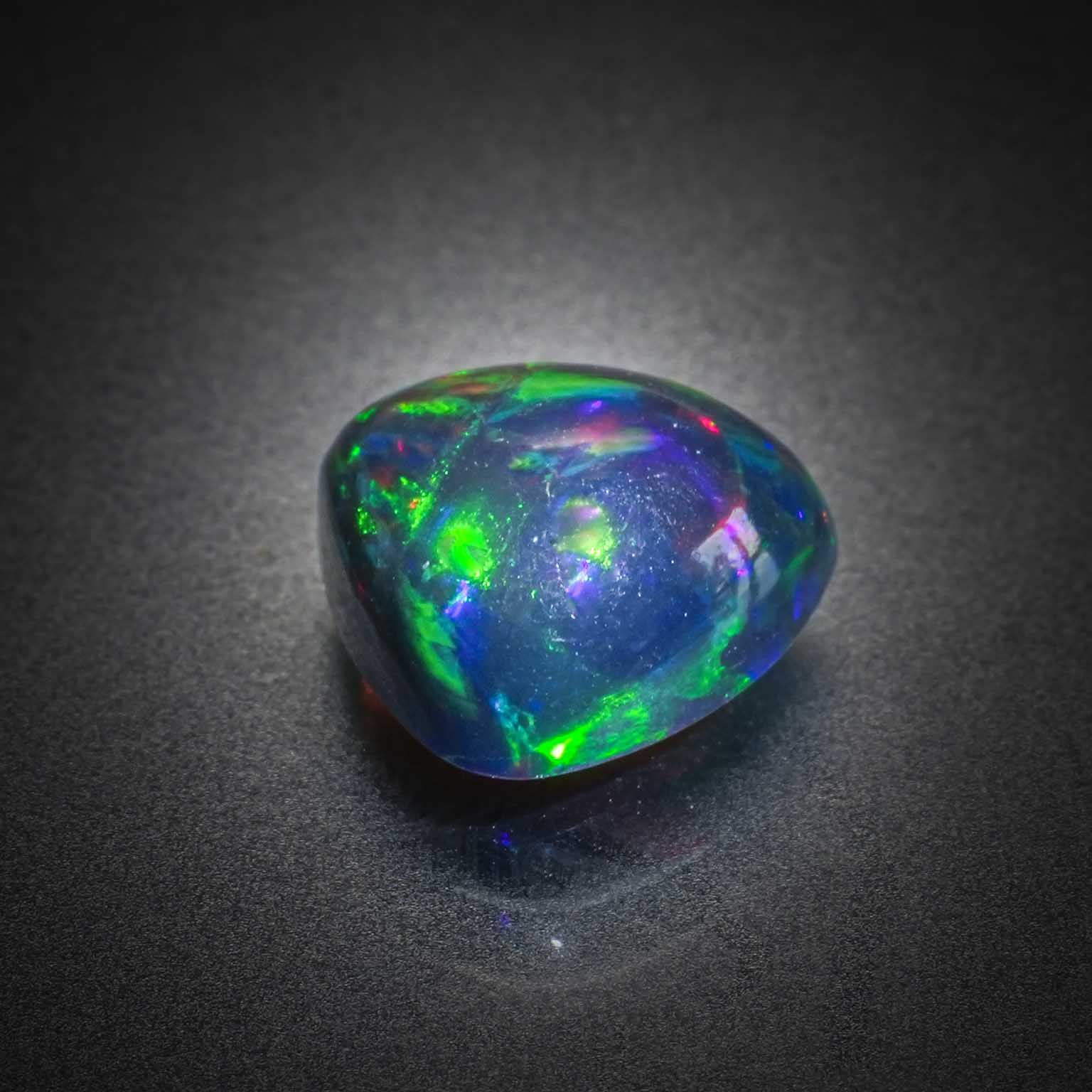 Opale noire triangulaire cabochon sur papier. - Lazuli