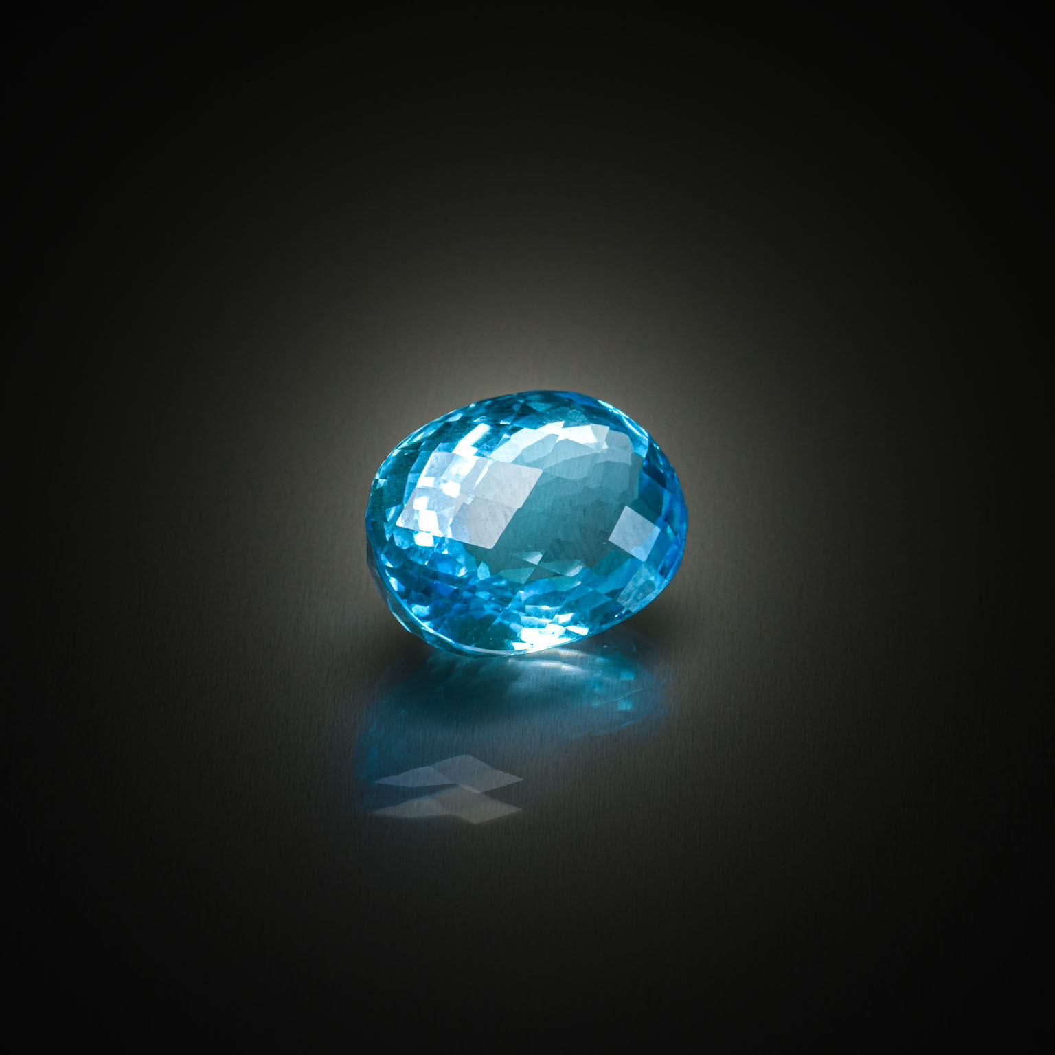Topaze bleue (Swiss Blue) ovale facettée sur papier. - Lazuli