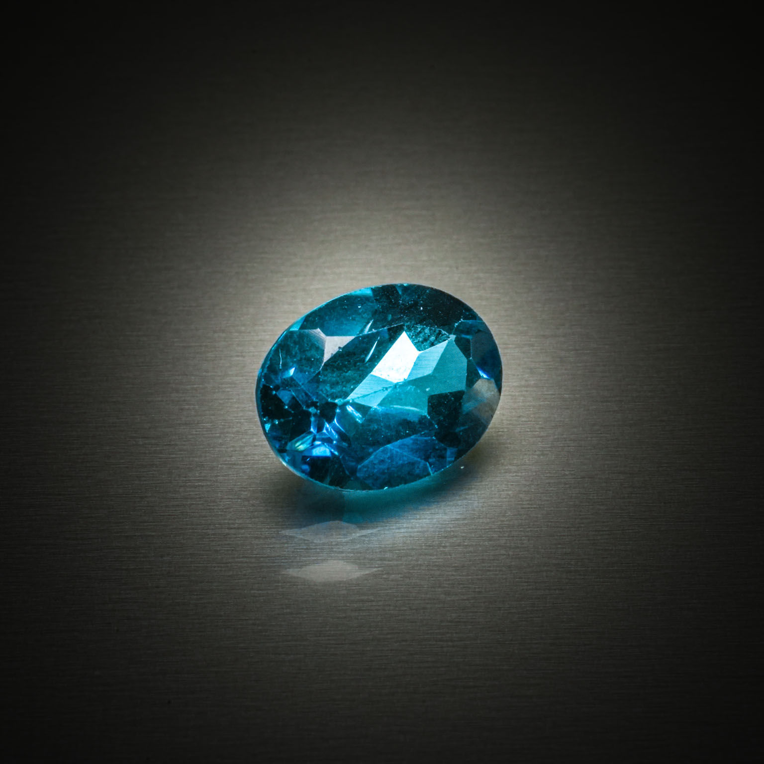 Topaze bleue (Swiss Blue) ovale facettée sur papier. - Lazuli