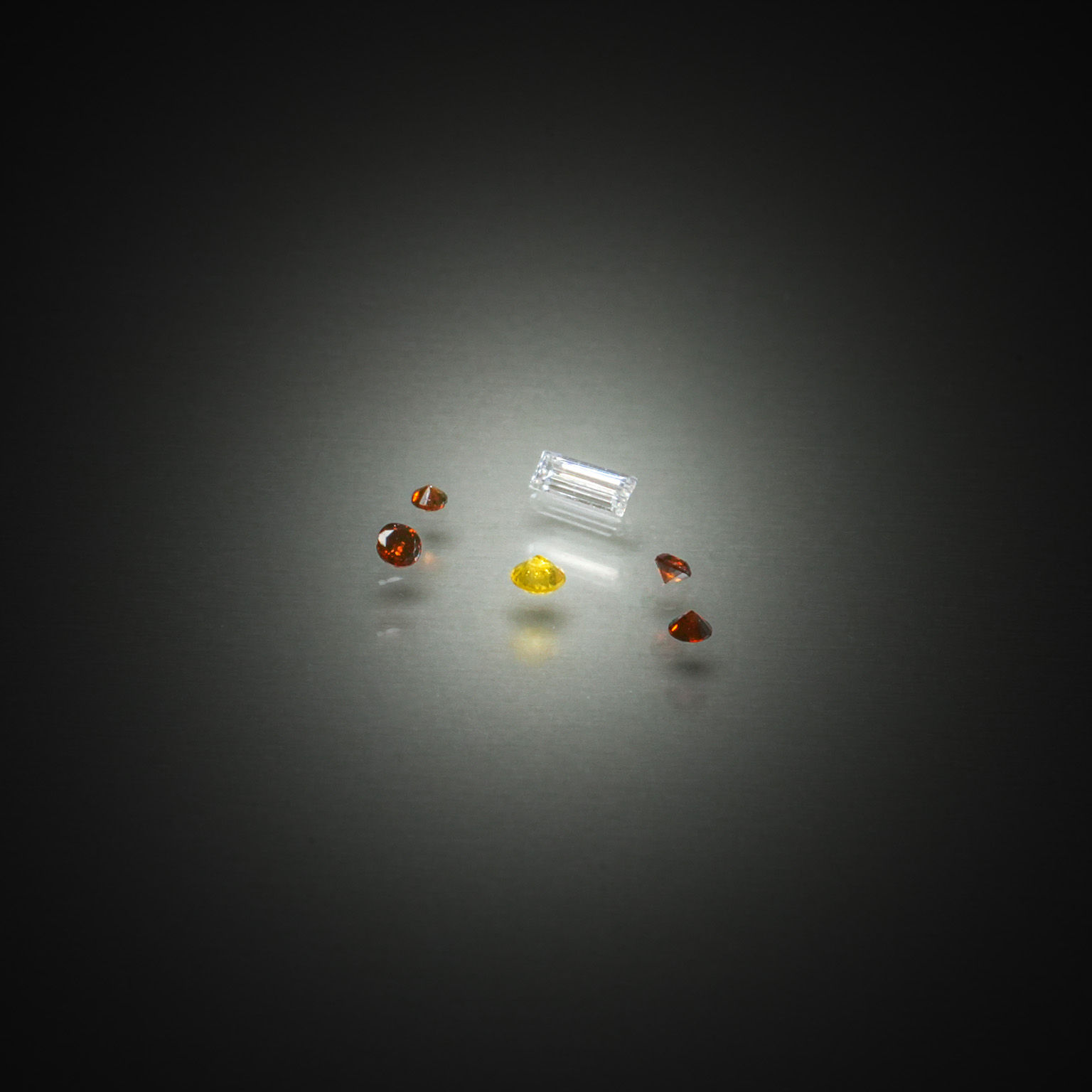 Lot de quatre diamants caramels ronds, un diamant jaune et un diamant baguette sur papier. - Lazuli