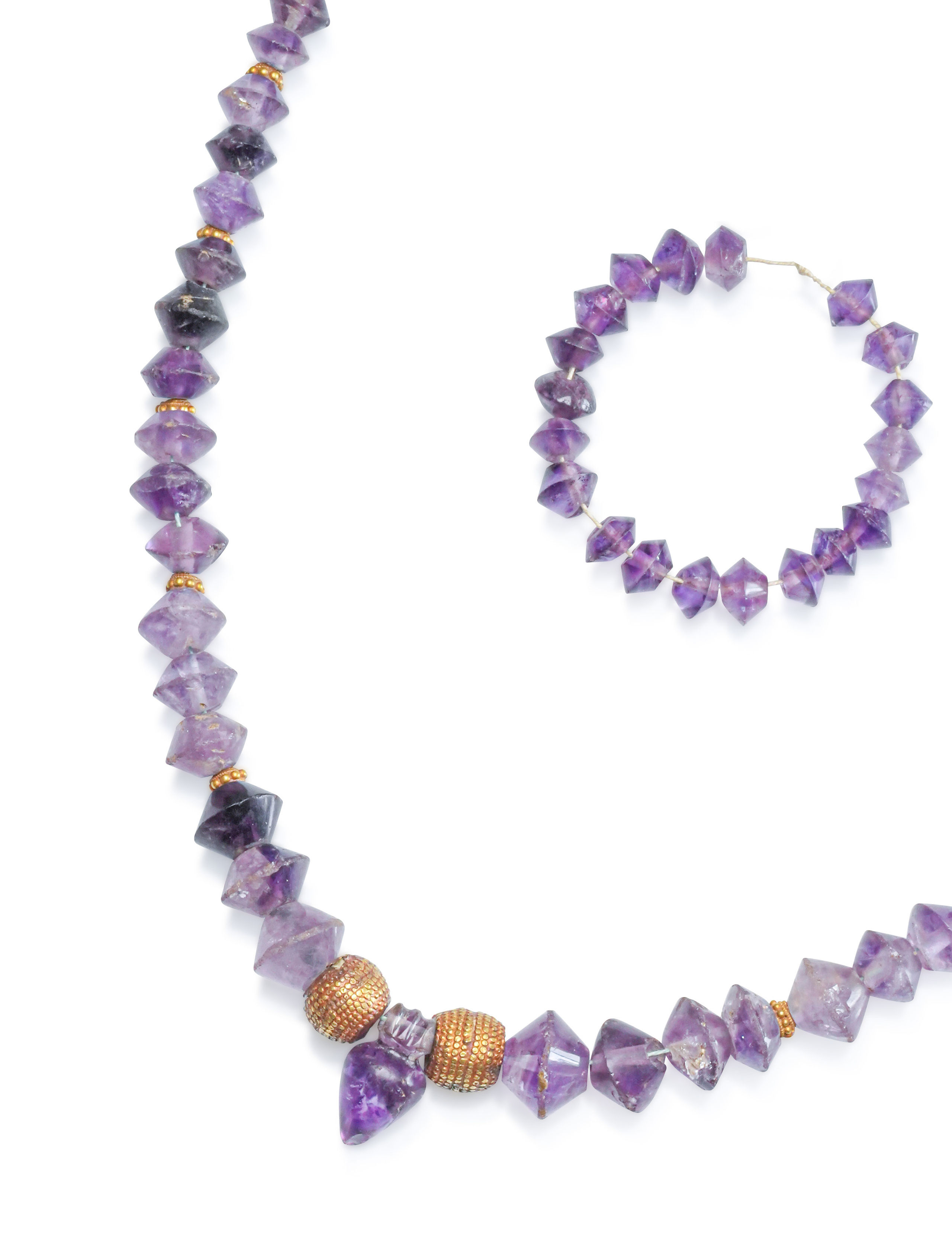Collier composé de perles biconiques, de deux grosses perles sphériques, d’un cœur IB, et de perles intercalaires granulées. Améthyste et or. Art hellénistique. L. environ 50 cm. On y joint un petit bracelet d’améthyste. - Lazuli