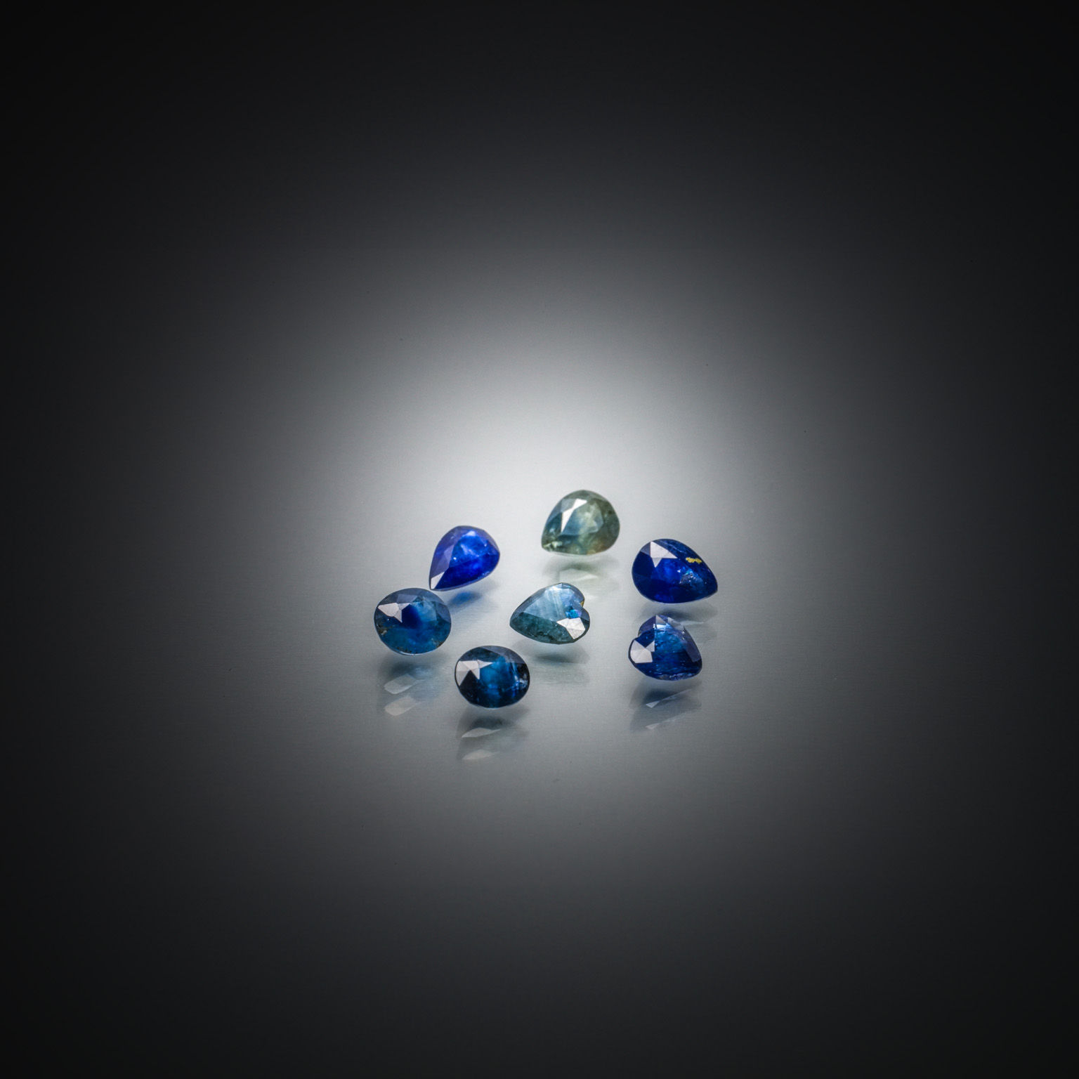 Lot de sept saphirs bleus/verts sur papier. - Lazuli