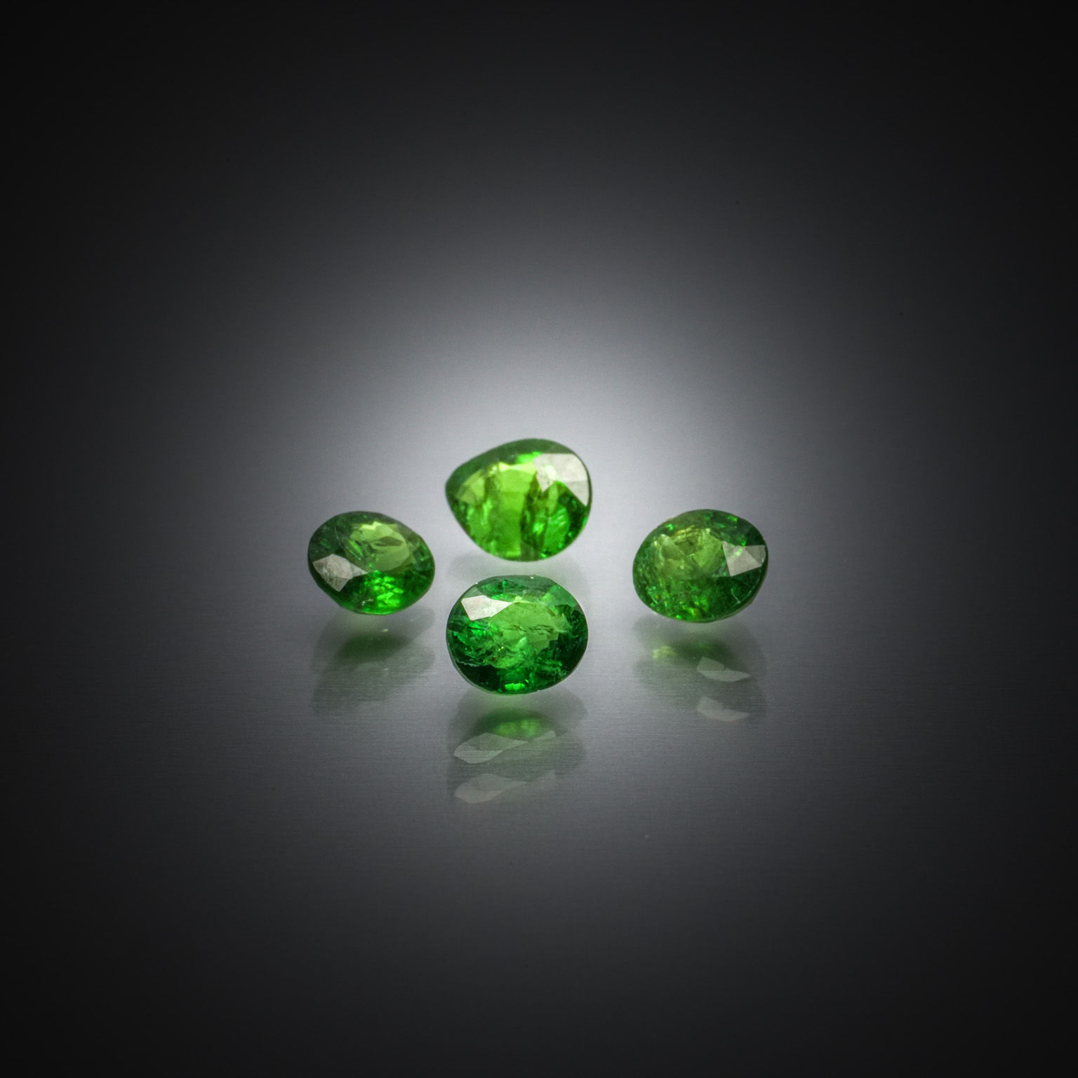 Lot de quatre grenats tsavorites ovales et poire sur papier. - Lazuli