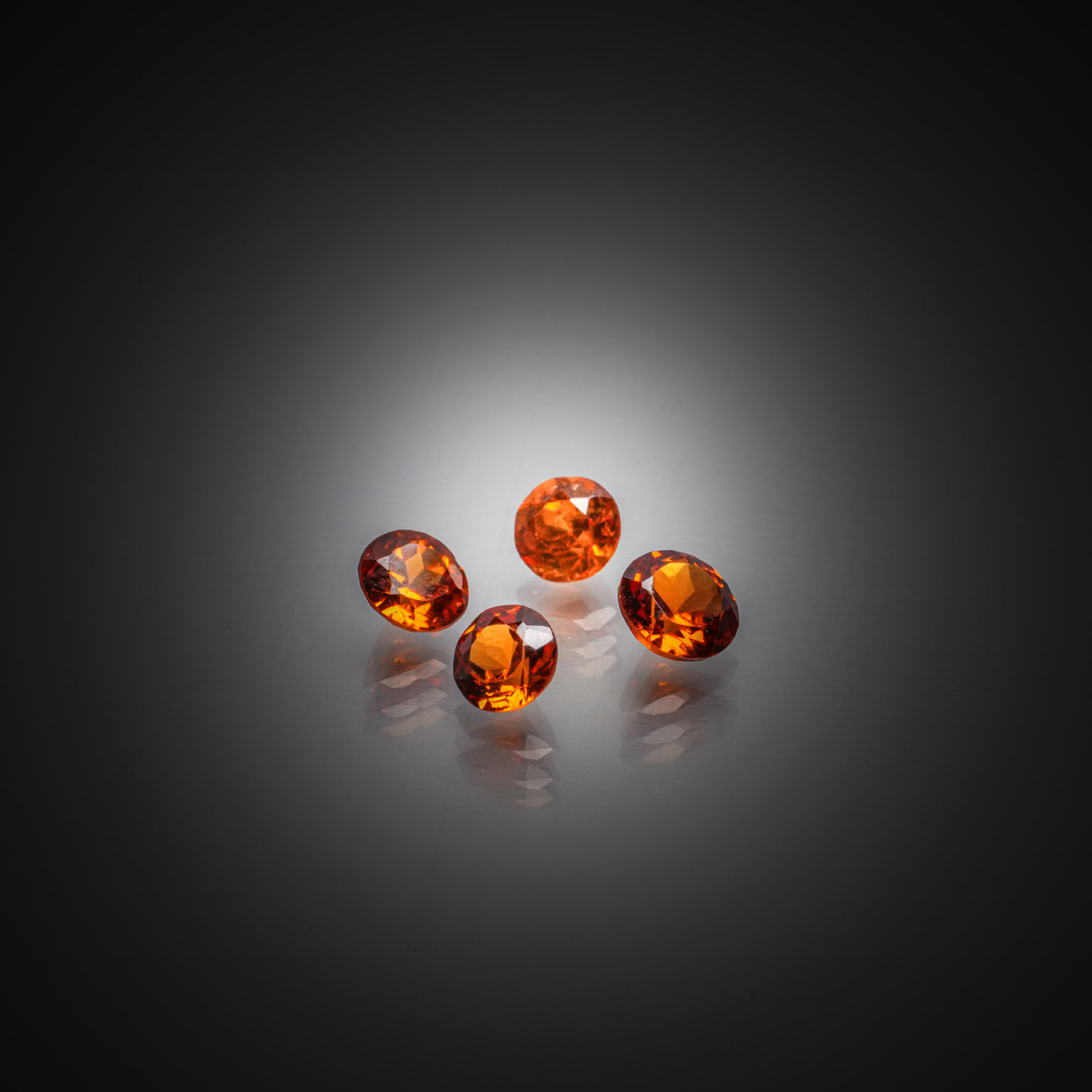 Lot de quatre grenats orange vifs ronds sur papier. - Lazuli