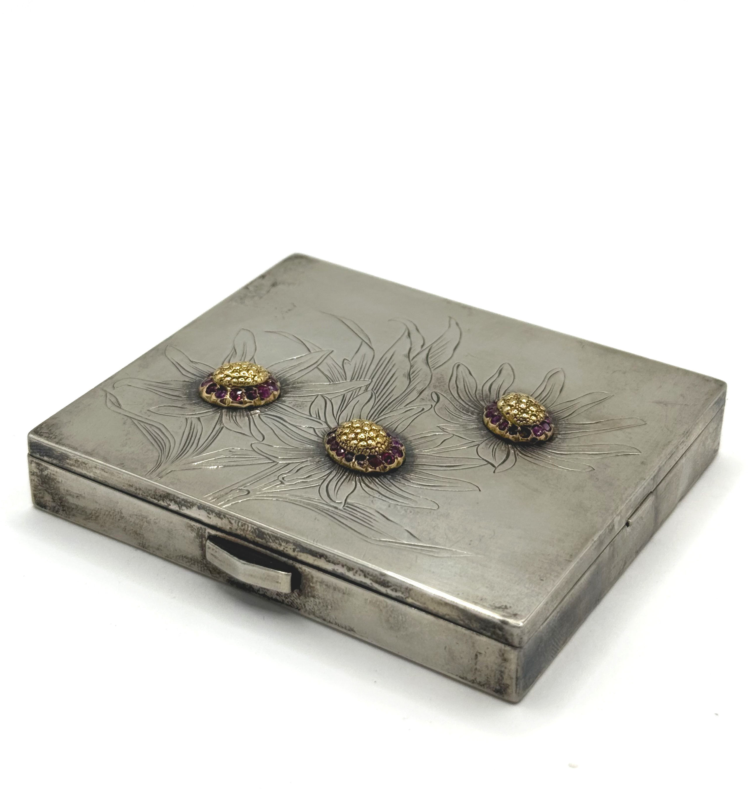 Poudrier en argent (800 millièmes) à décor gravé de fleurs, les pistils en bas relief en or (750 millièmes) orné de rubis ronds, le revers guilloché. - Lazuli