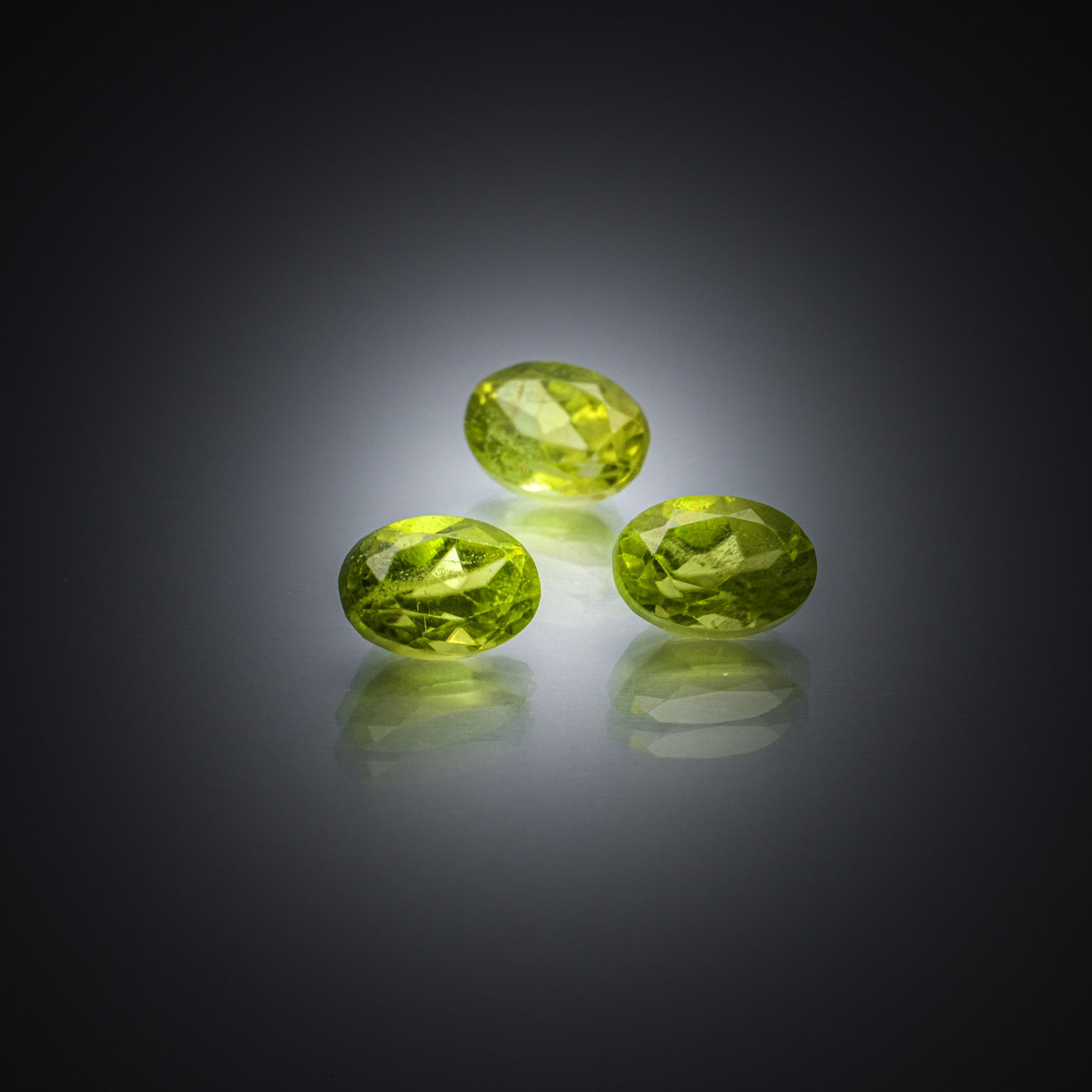 Lot de trois sphènes verts ovales sur papier. - Lazuli
