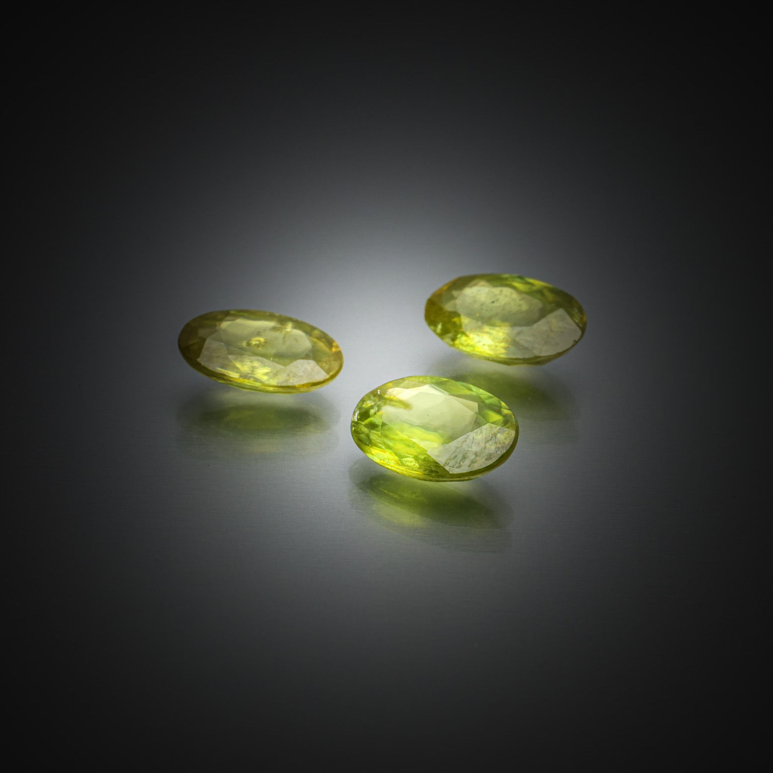 Lot de trois sphènes verts ovales sur papier. - Lazuli