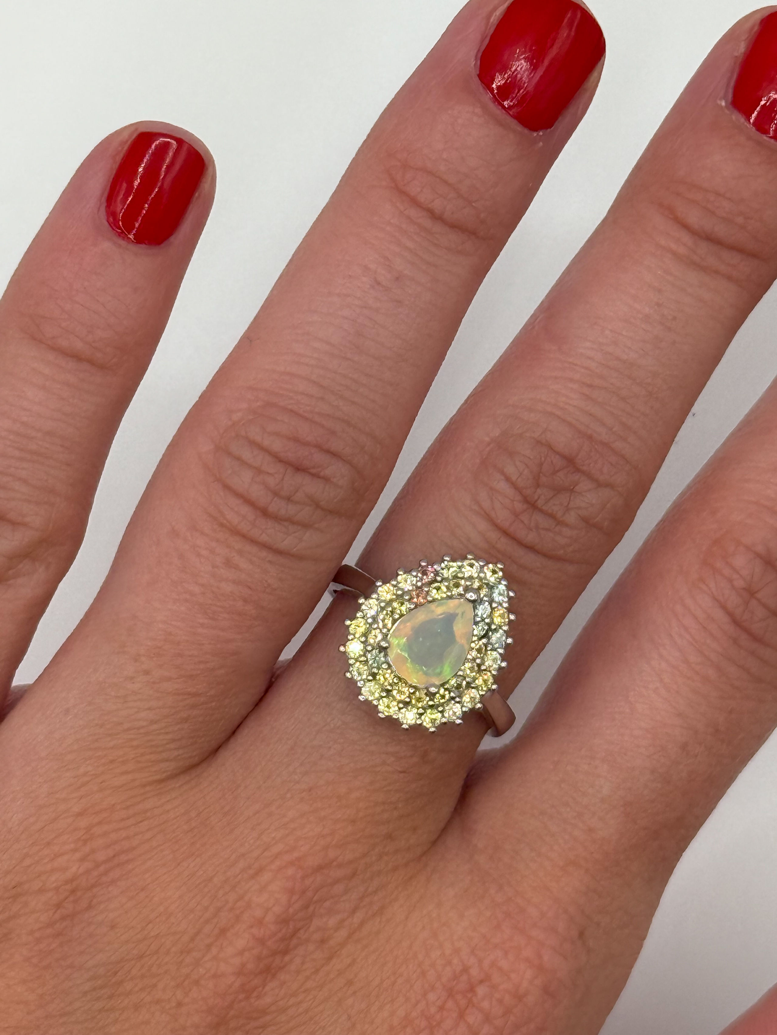 Bague en argent (925 millième) ornée d&rsquo;une opale poire dans un double entourage de saphirs de couleurs ronds. - Lazuli