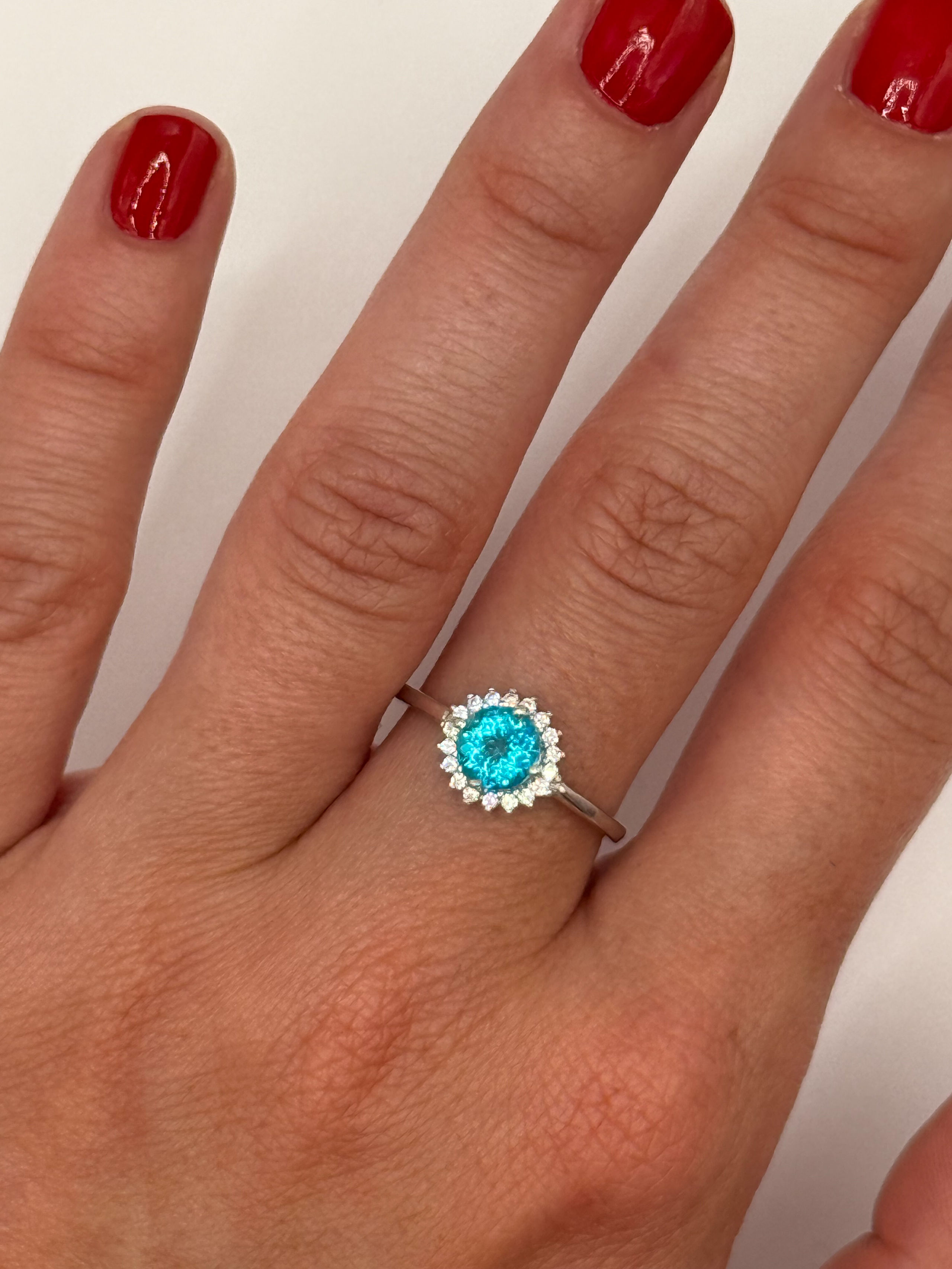 Bague en argent (925 millième) ornée d&rsquo;une topaze (Paraïba Blue) ronde dans un entourage de pierres blanches rondes. - Lazuli