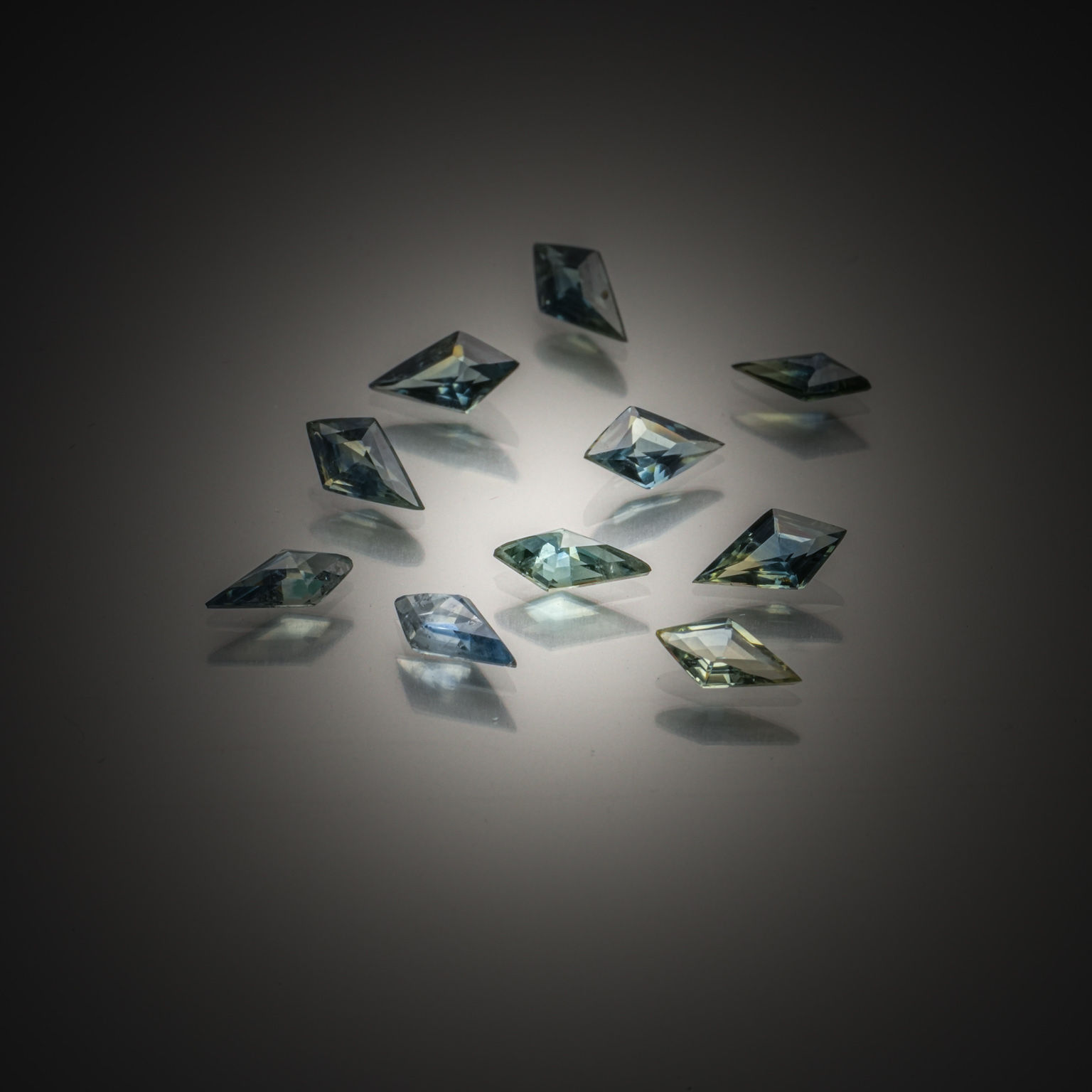 Lot de trois saphirs verts ovales sur papier. - Lazuli