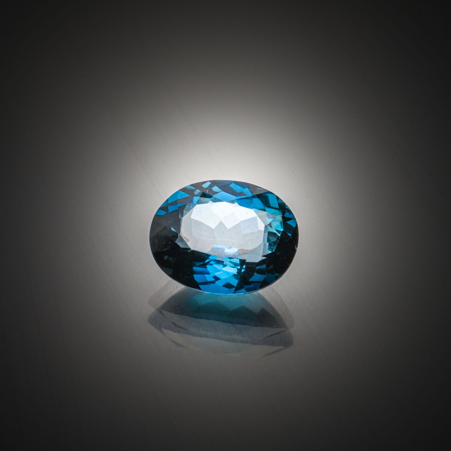 Topaze bleue ovale concave sur papier. - Lazuli