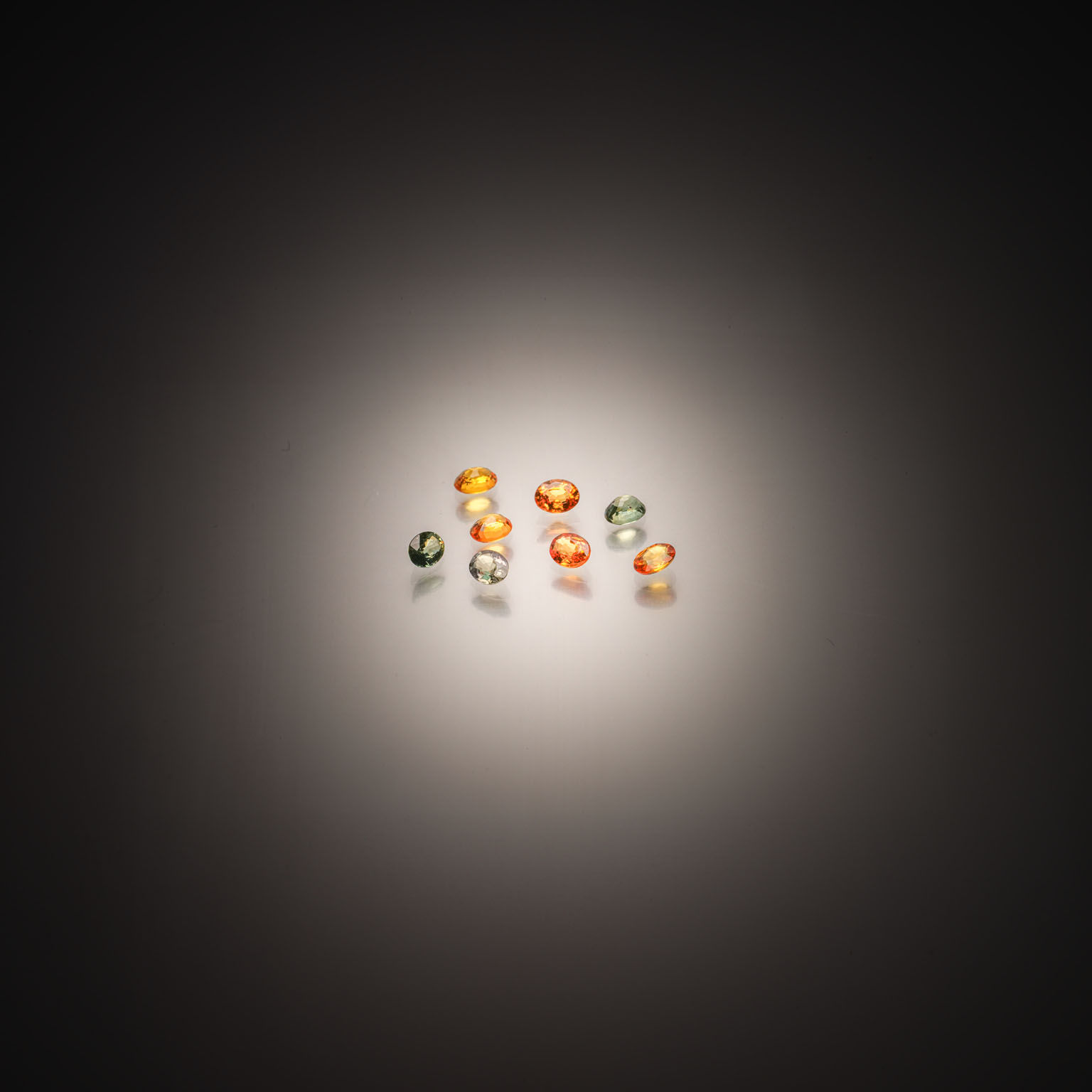 Lot de huit saphirs verts et orange sur papier. - Lazuli