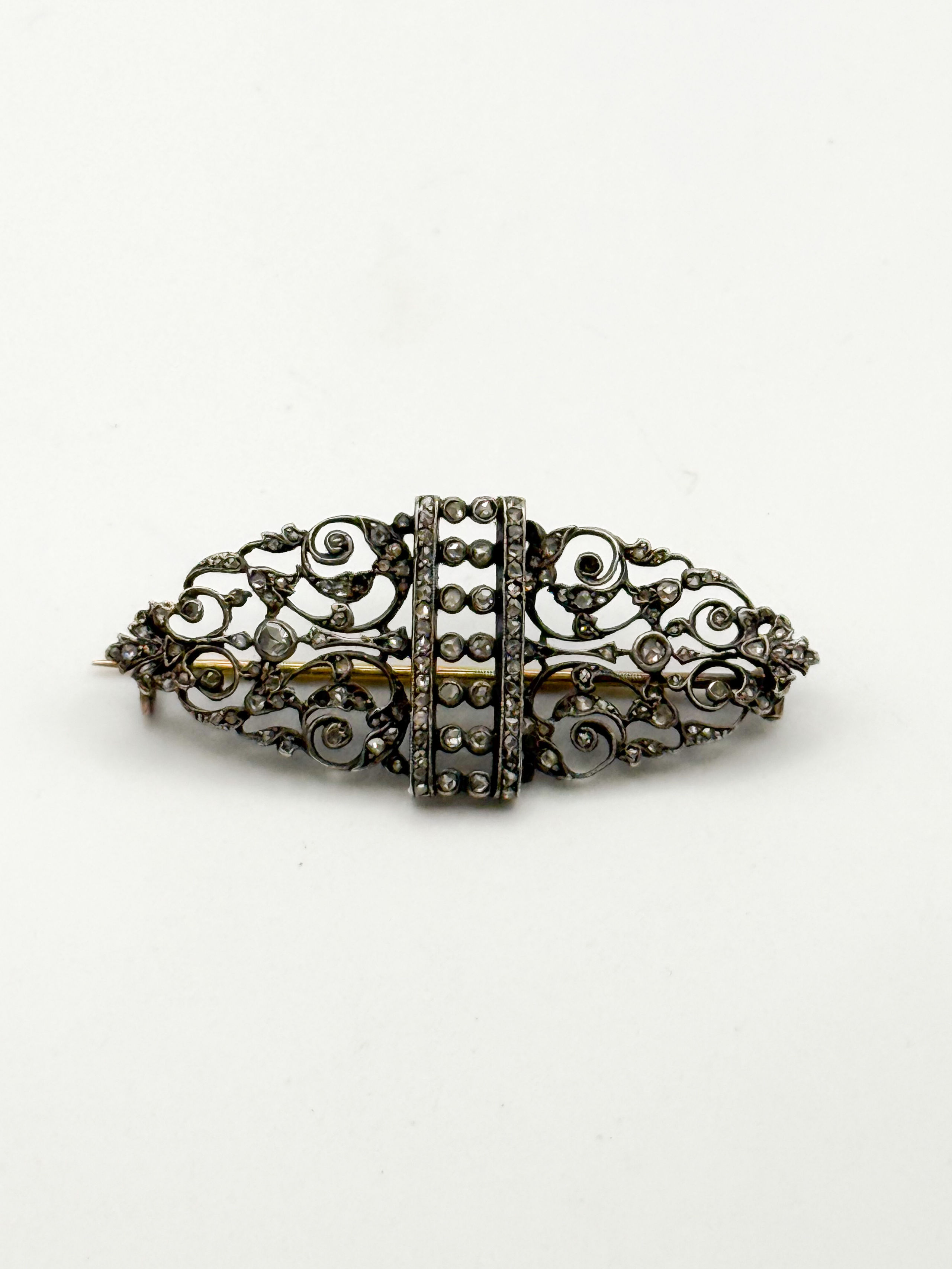 Broche ajourée en or jaune (750 millièmes) et argent à décor de volutes et ornée de diamants tailles ancienne. - Lazuli