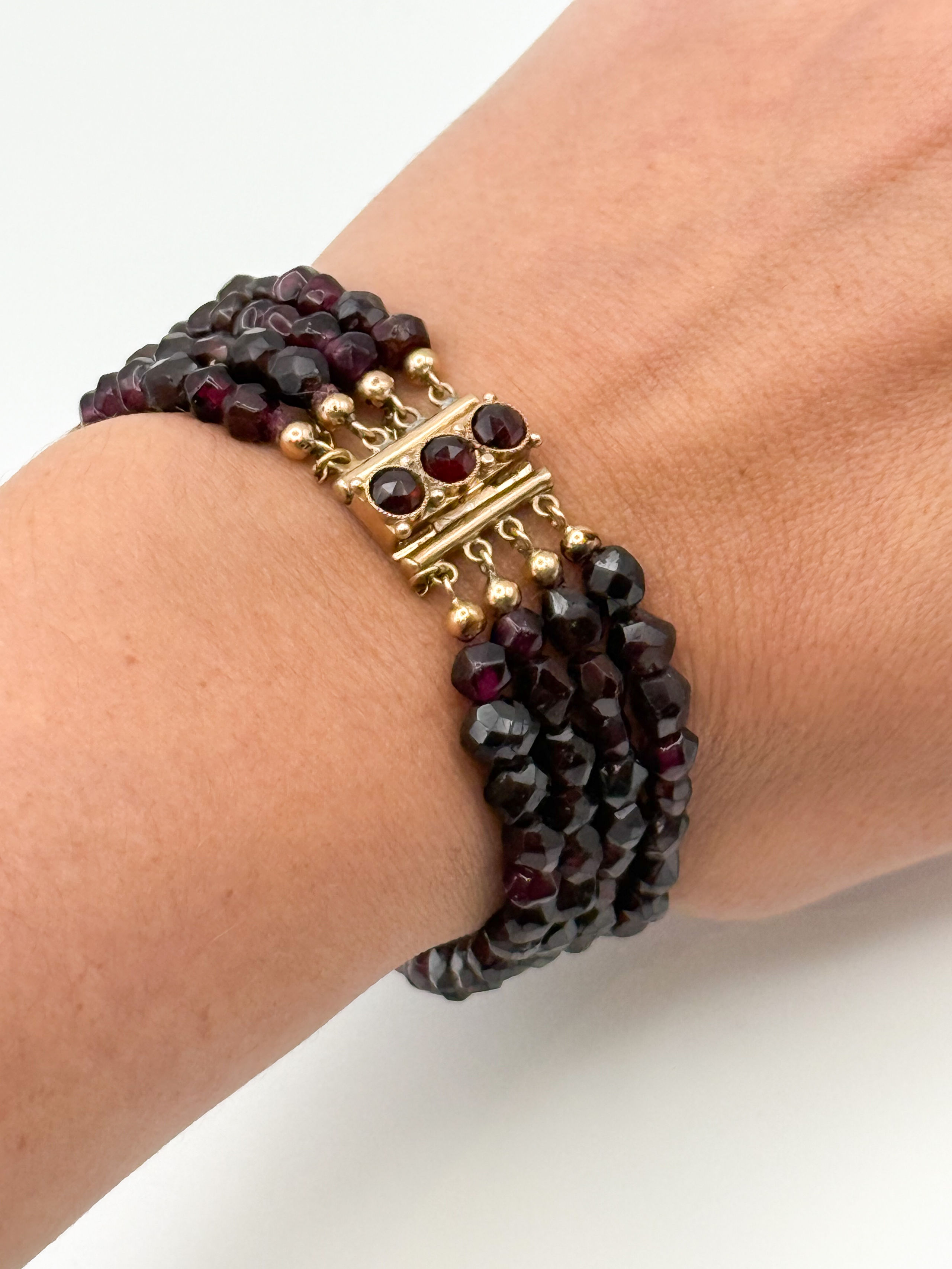 Bracelet quatre rangs de perles de grenat facettées, le fermoir en or jaune (750 millièmes) orné de trois grenats. - Lazuli