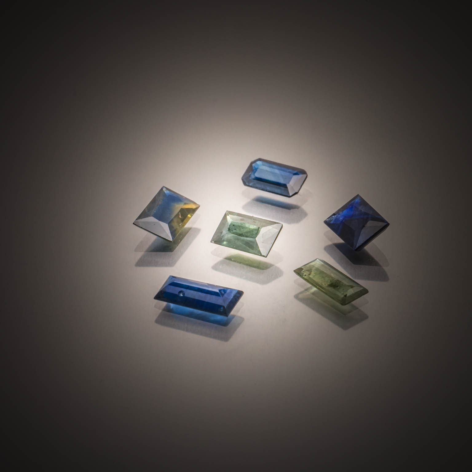 Lot de trois tourmalines paraïbas brutes et une tanzanite brute sur papier. - Lazuli