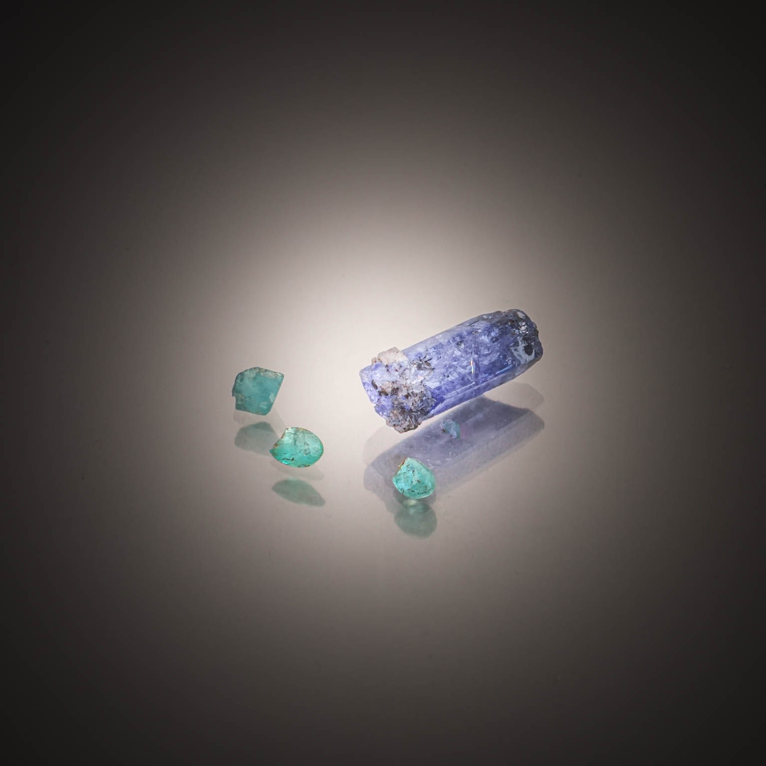 Lot de trois tourmalines paraïbas brutes et une tanzanite brute sur papier. - Lazuli