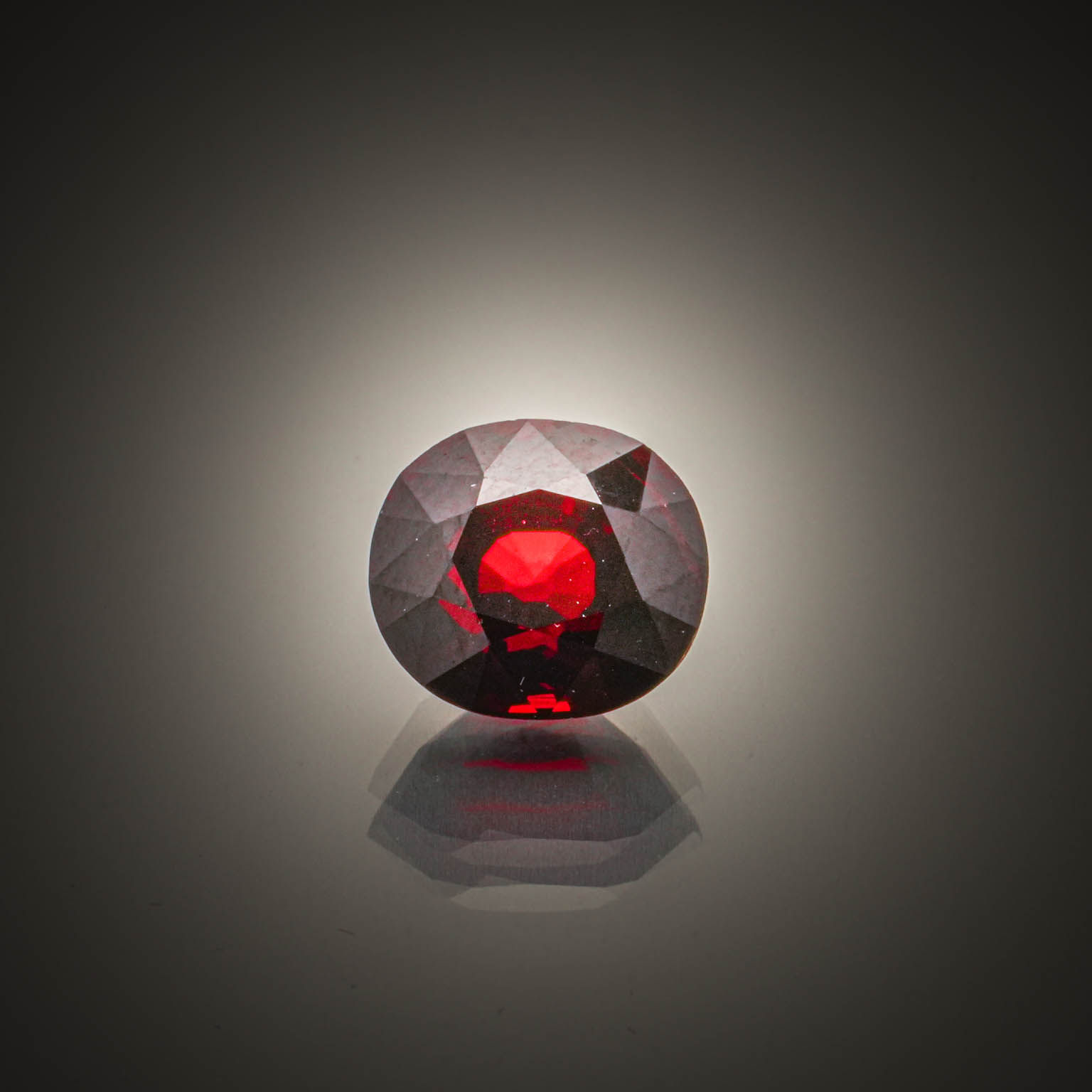 Grenat spessartite rouge/orange ovale sur papier. - Lazuli