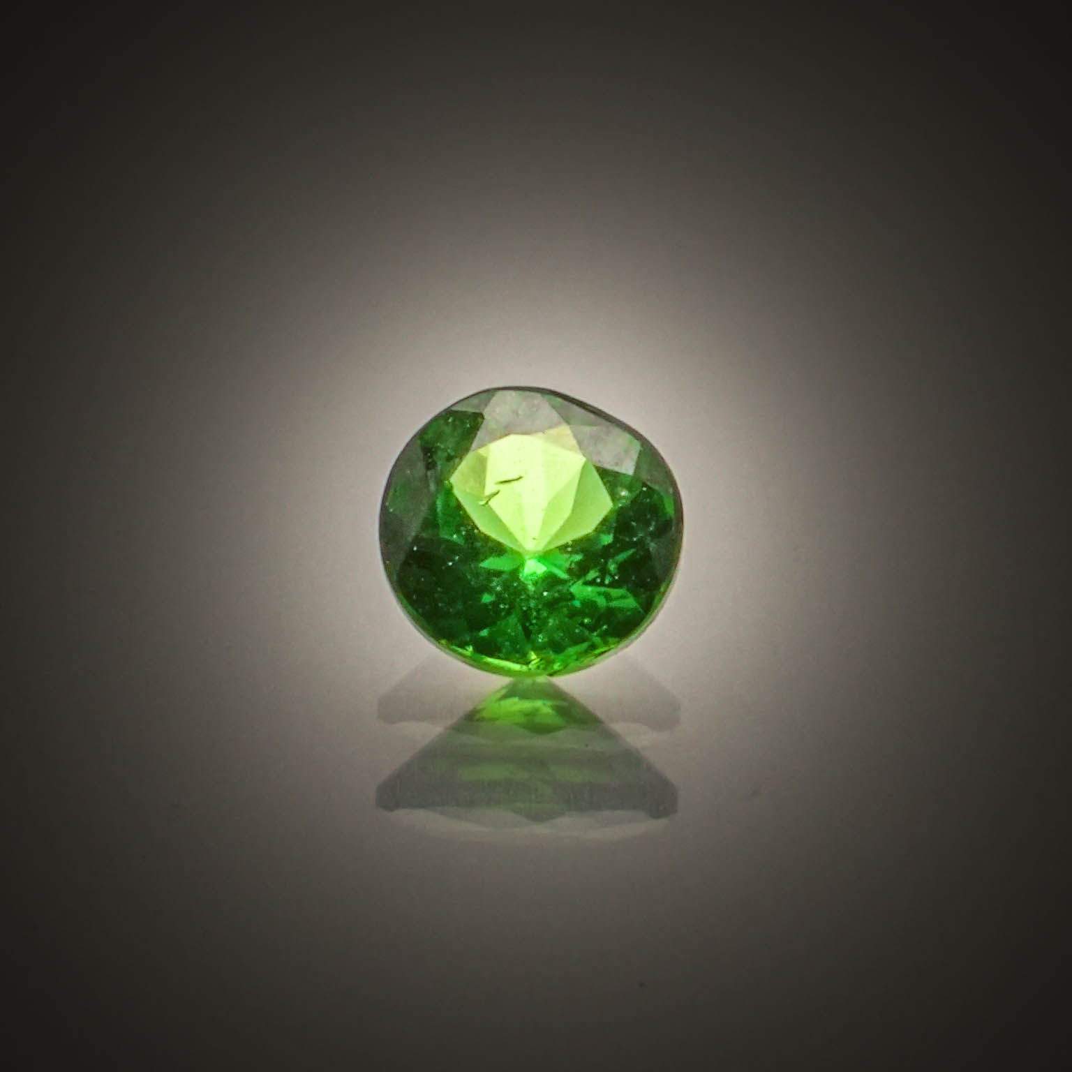 Grenat tsavorite rond sur papier. - Lazuli