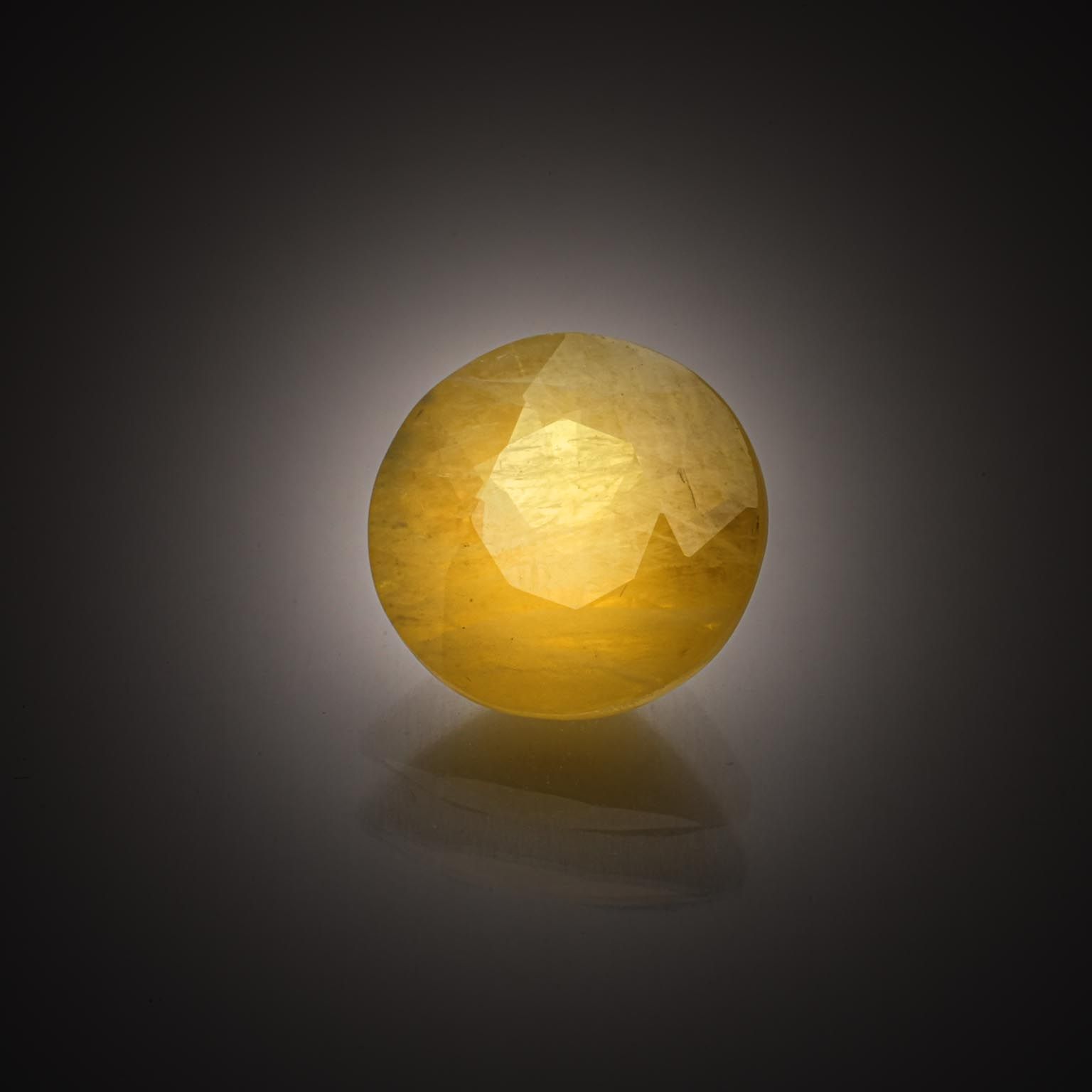 Saphir jaune rond sur papier. - Lazuli