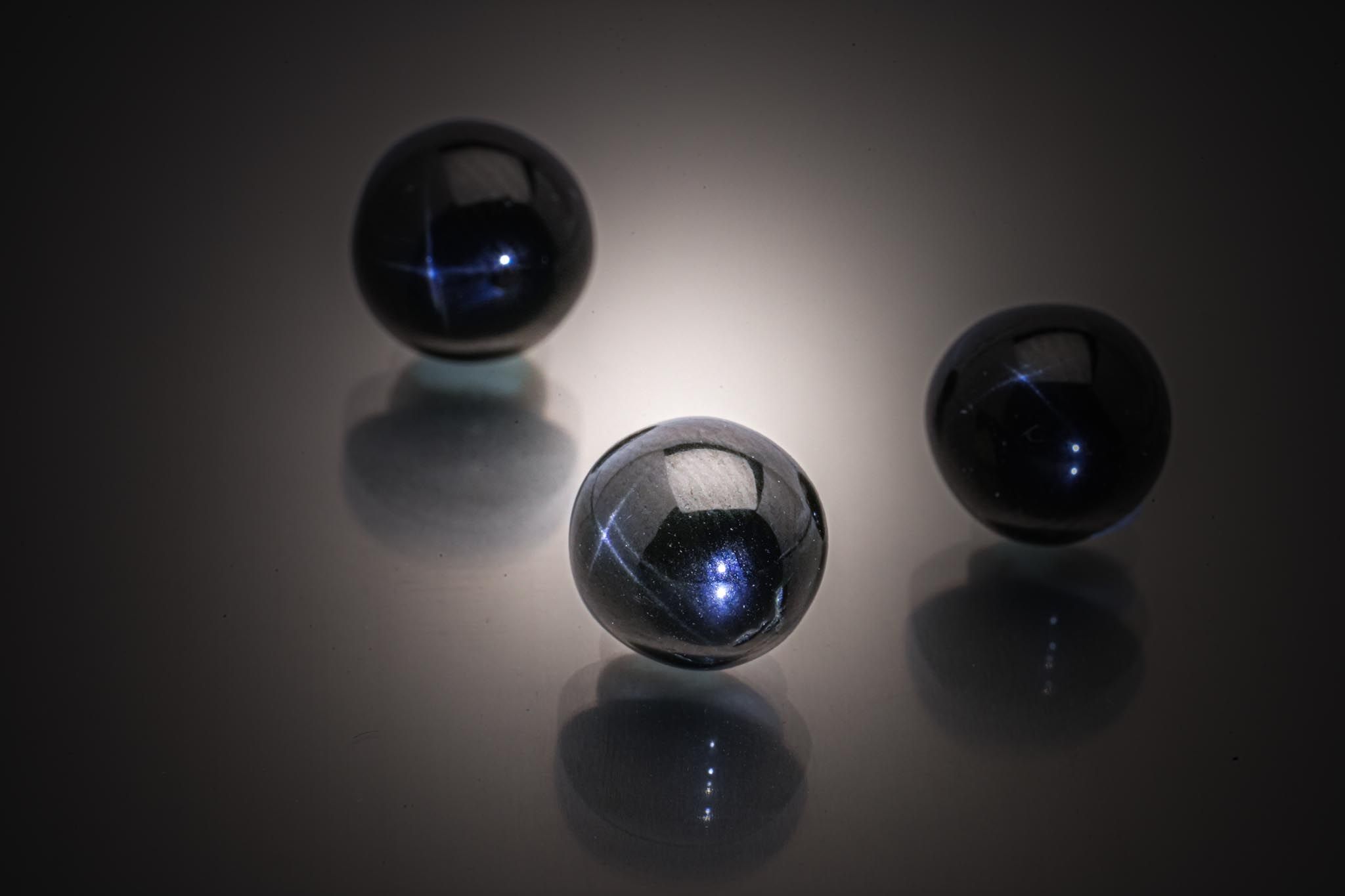 Lot de trois diopsides noirs étoilés (4 branches) ronds cabochons sur papier. - Lazuli