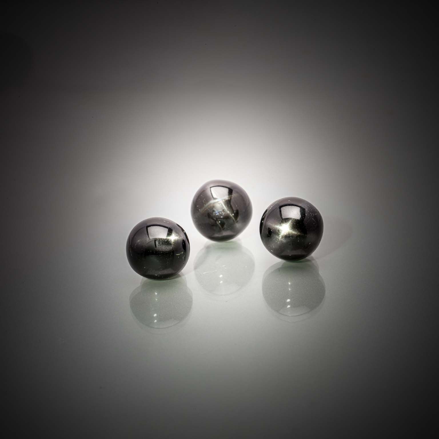 Lot de trois diopsides noirs étoilés (4 branches) ronds cabochons sur papier. - Lazuli