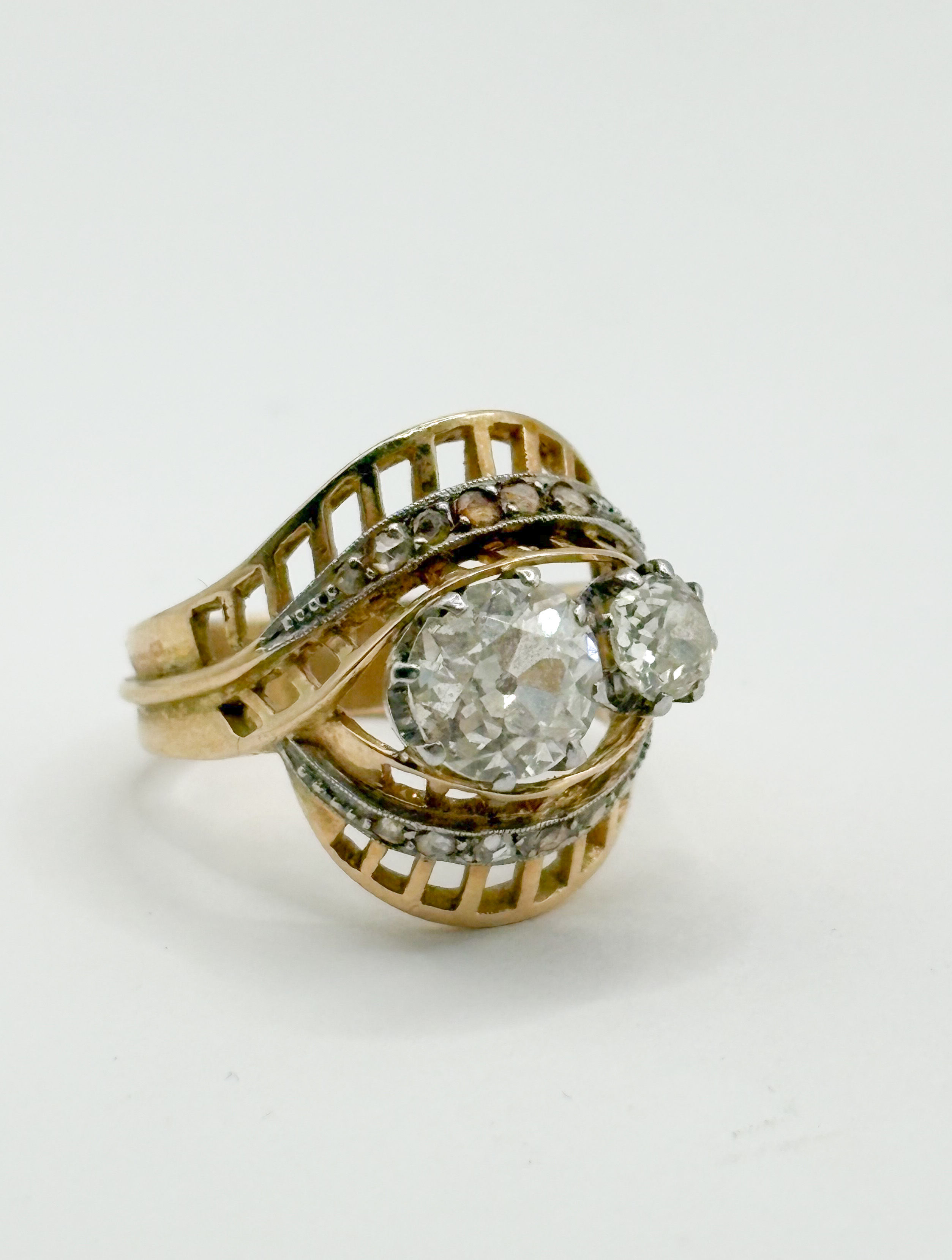 Bague ajourée en or jaune (750 millièmes) et platine ornée de deux diamants taille ancienne et de diamants taillés en rose. - Lazuli