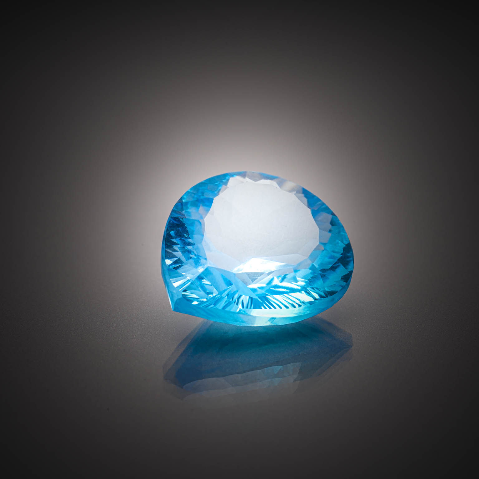 Topaze bleue (Swiss Blue) poire concave sur papier. - Lazuli