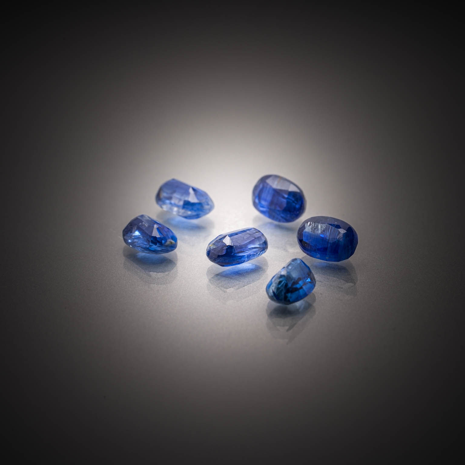 Lot de dix saphirs bleu-vert ronds sur papier. - Lazuli