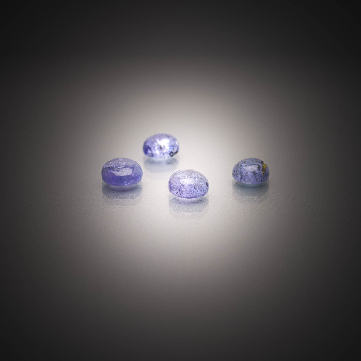 Lot de quatre tanzanites rondes cabochons sur papier. - Lazuli