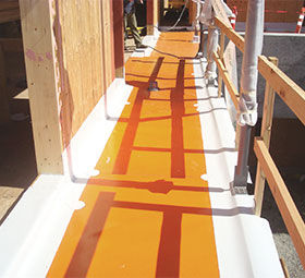 A technician in protective gear installs solar panels on a house roof, promoting sustainability.