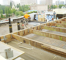 Workers wearing PPE install solar panels for sustainable energy at a construction site.