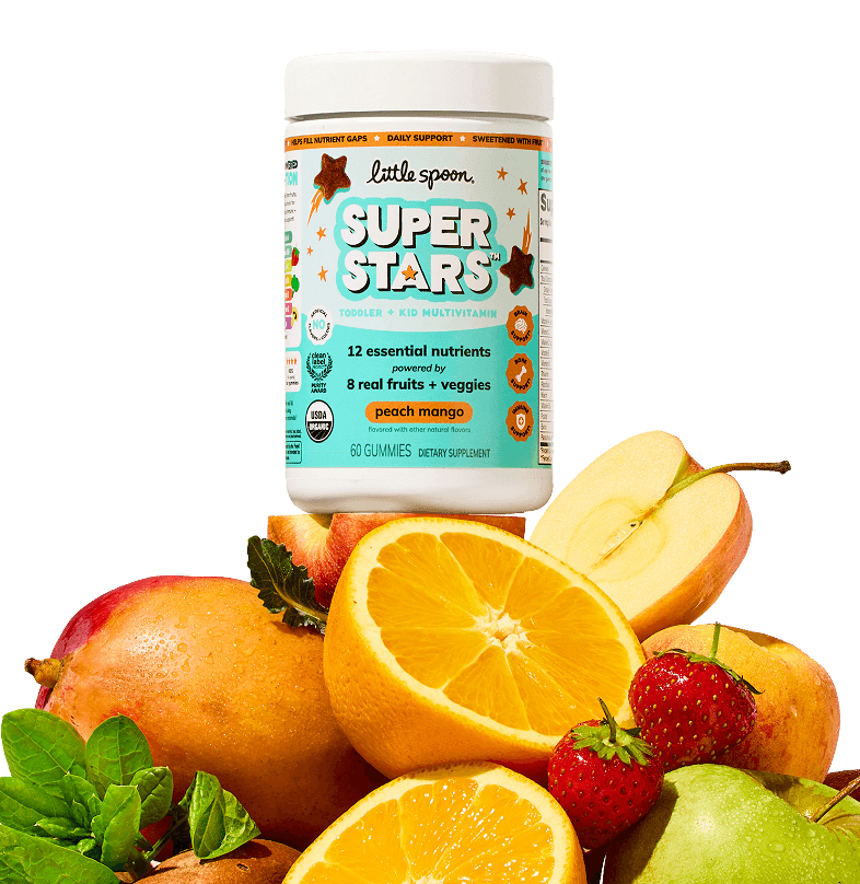 A jar of Little Spoon Superstars peach mango toddler and kid multivitamin gummies surrounded by fresh oranges, mango, apple, strawberries and peach