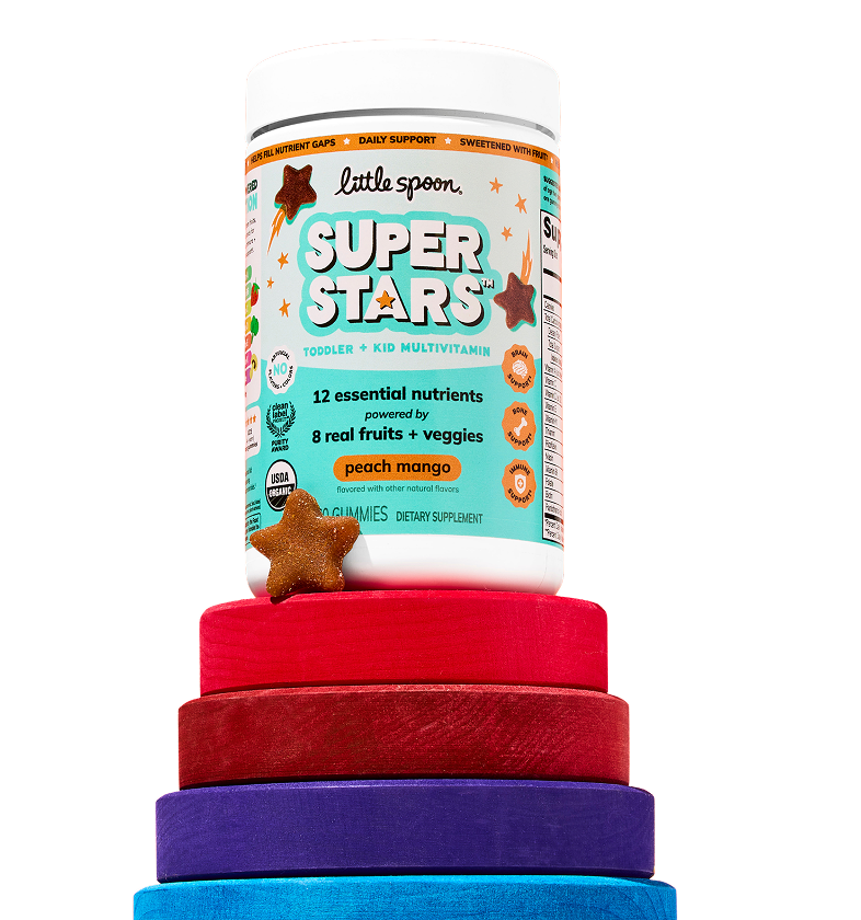 Jar of Little Spoon Superstars Toddler + Kid Multivitamin gummies in peach mango, with a star-shaped gummy, sitting on top of a stack of colorful rings