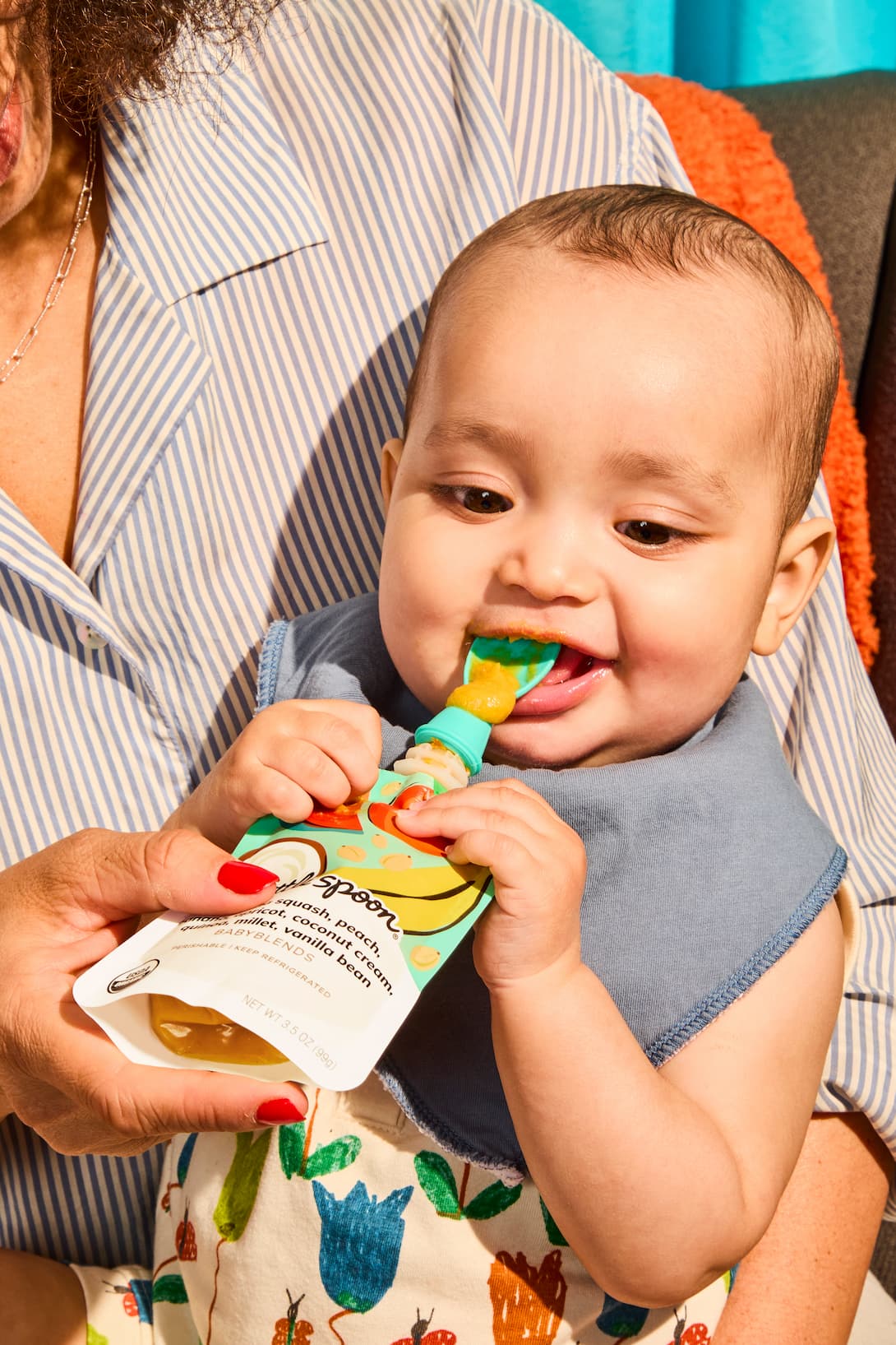 Baby eating from a Little Spoon Babyblends pouch while being held by a parent.