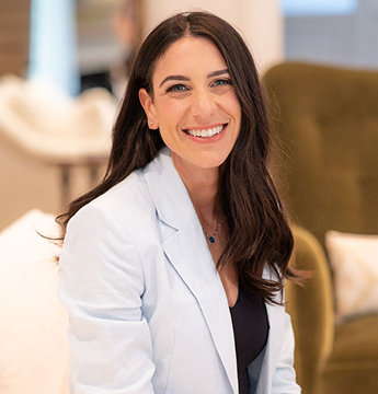 Picture of Jennifer Friedman smiling at the camera while holding a baby.