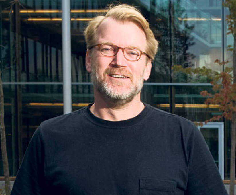 Bruce Lanphear, Clinician Scientist for Early Childhood Health, raising awareness for Little Things Matter, standing outside a modern building, smiling in a black shirt and glasses.