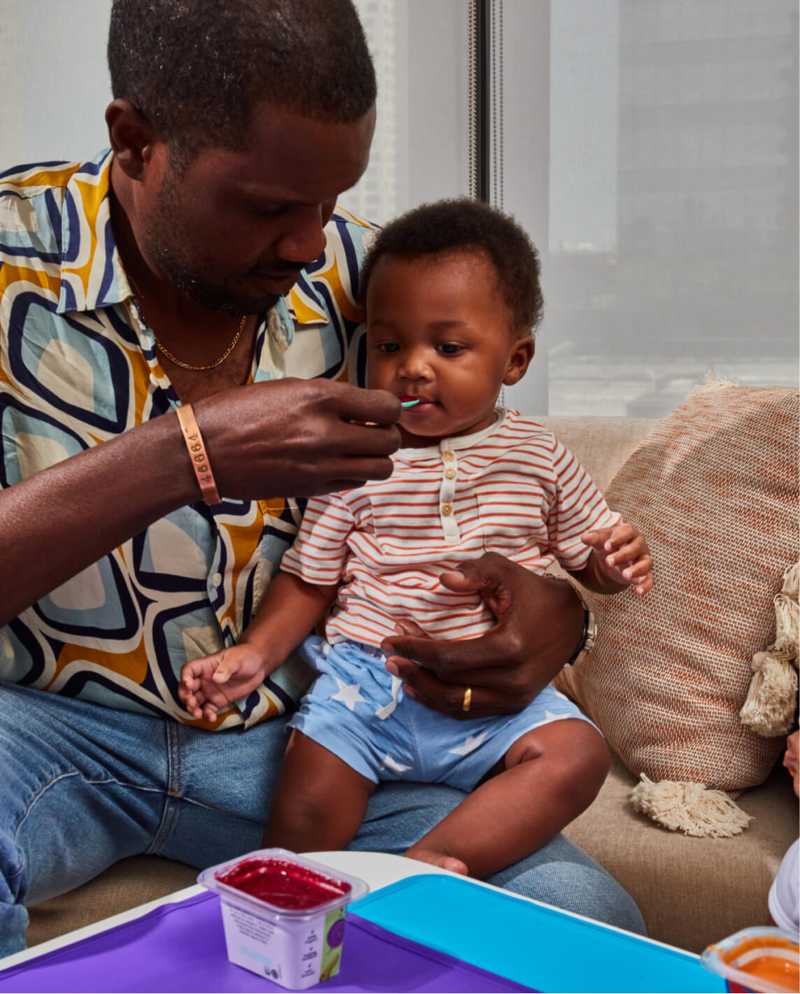 A dad lovingly holds on to his baby as he feeds his baby a Little Spoon blend.