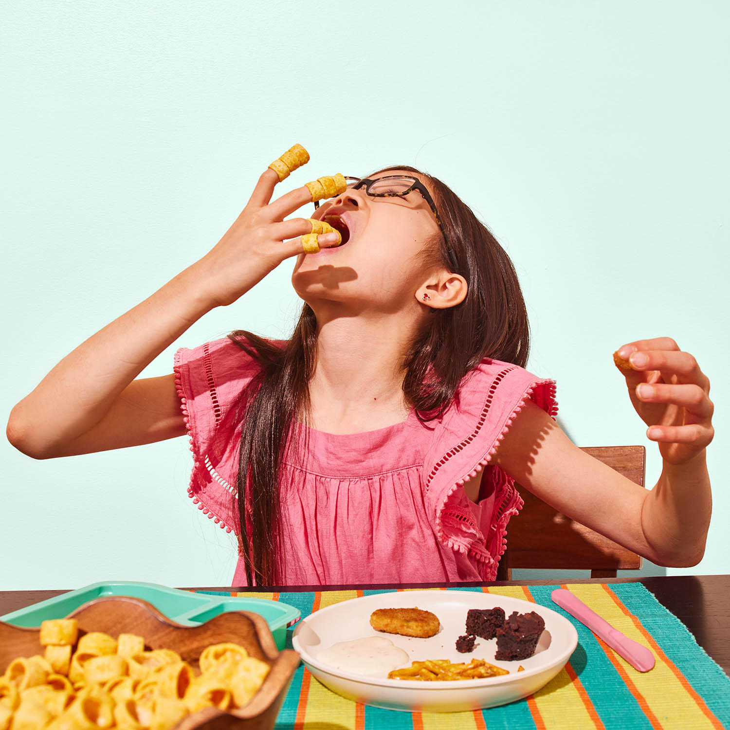 Girl eating Toddler Mac + Cheesy Veggie Loops Snack