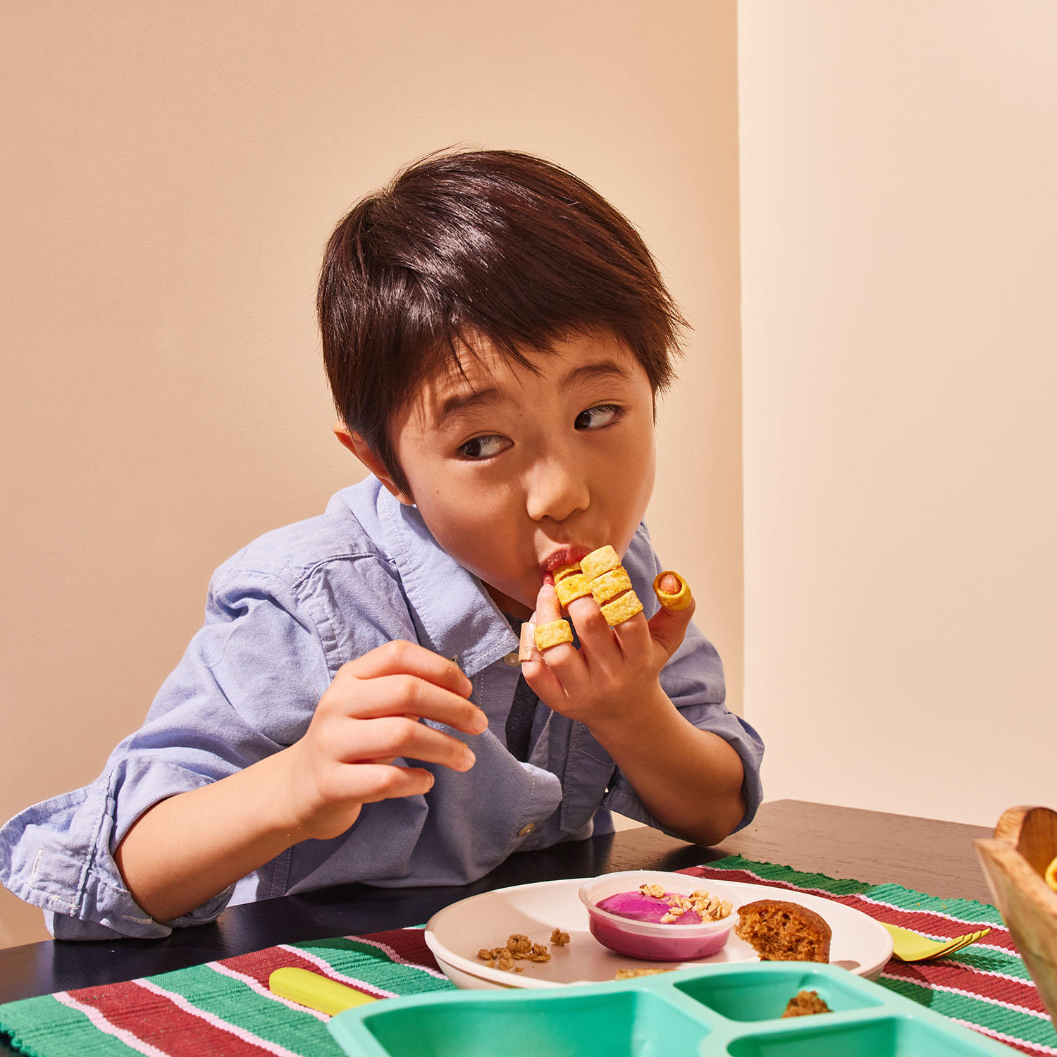 Boy eating Pancake Party Veggie Loops Snack off of fingers.