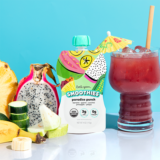 Paradise punch smoothie next to a paradise much drink and ingredients from the smoothie on a table