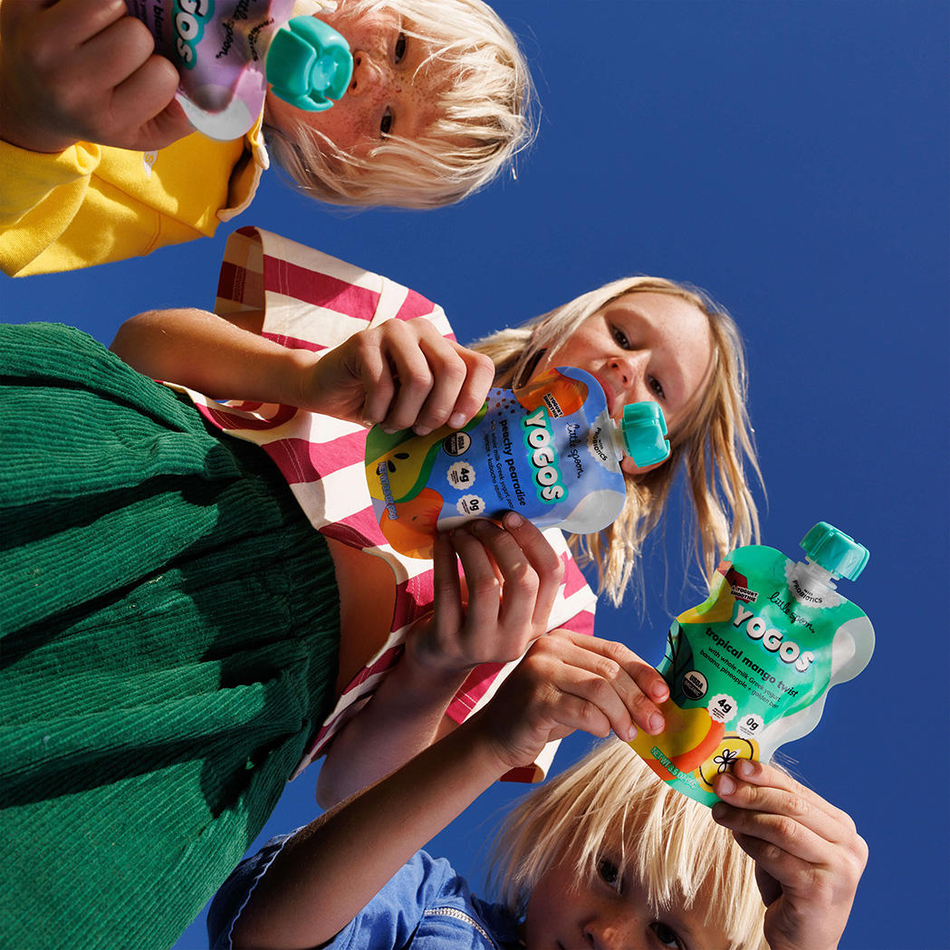 3 young children each holding a YoGos pouch looking down into the camera
