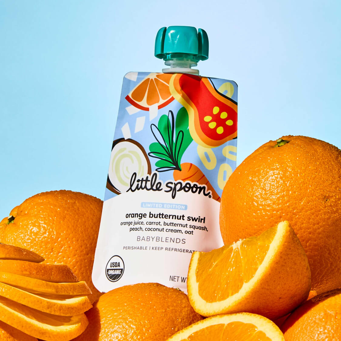 Limited Edition Orange Butternut Swirl Babyblend Pouch on top of whole and sliced fresh oranges
