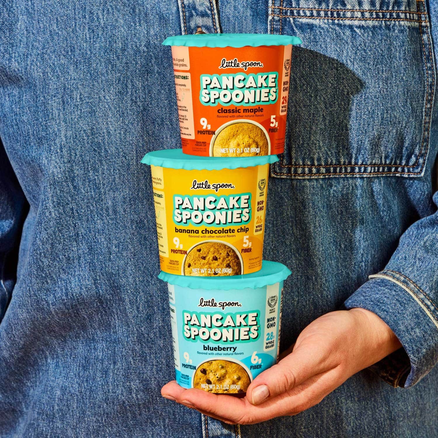 woman's hand holding all 3 containers of pancake spoonies flavors