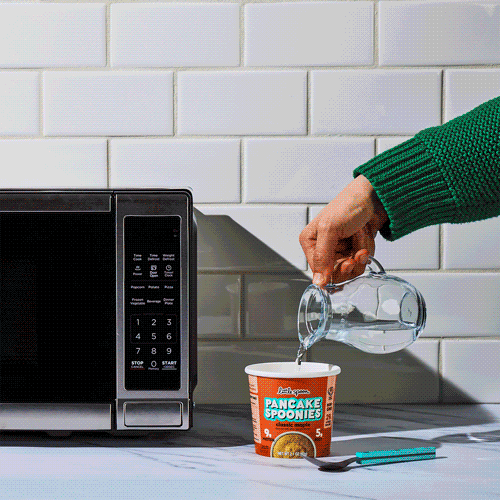 gif with a woman stirring water in a pancake spoonie, mixing it well and putting it in the microwave to cook it