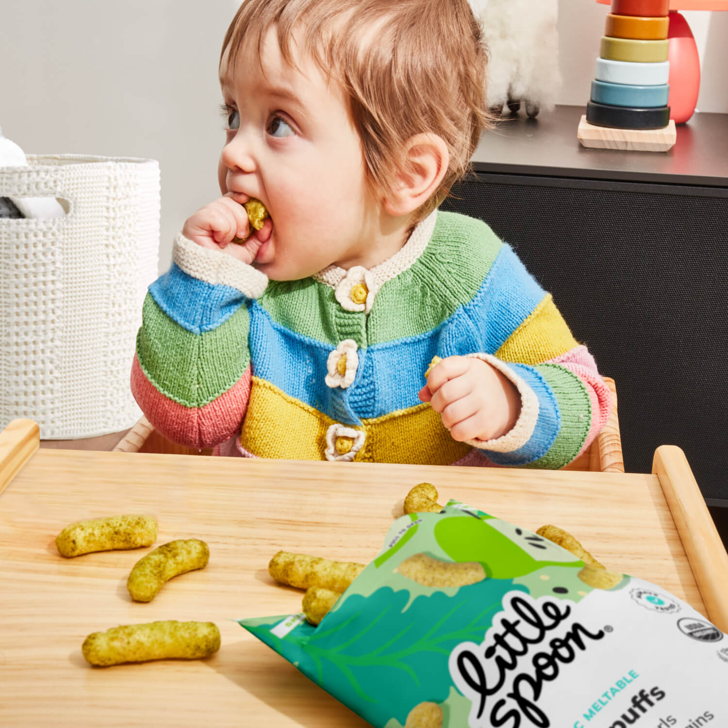 baby eating Kale Apple Meltable Baby Curls with open bag on table
