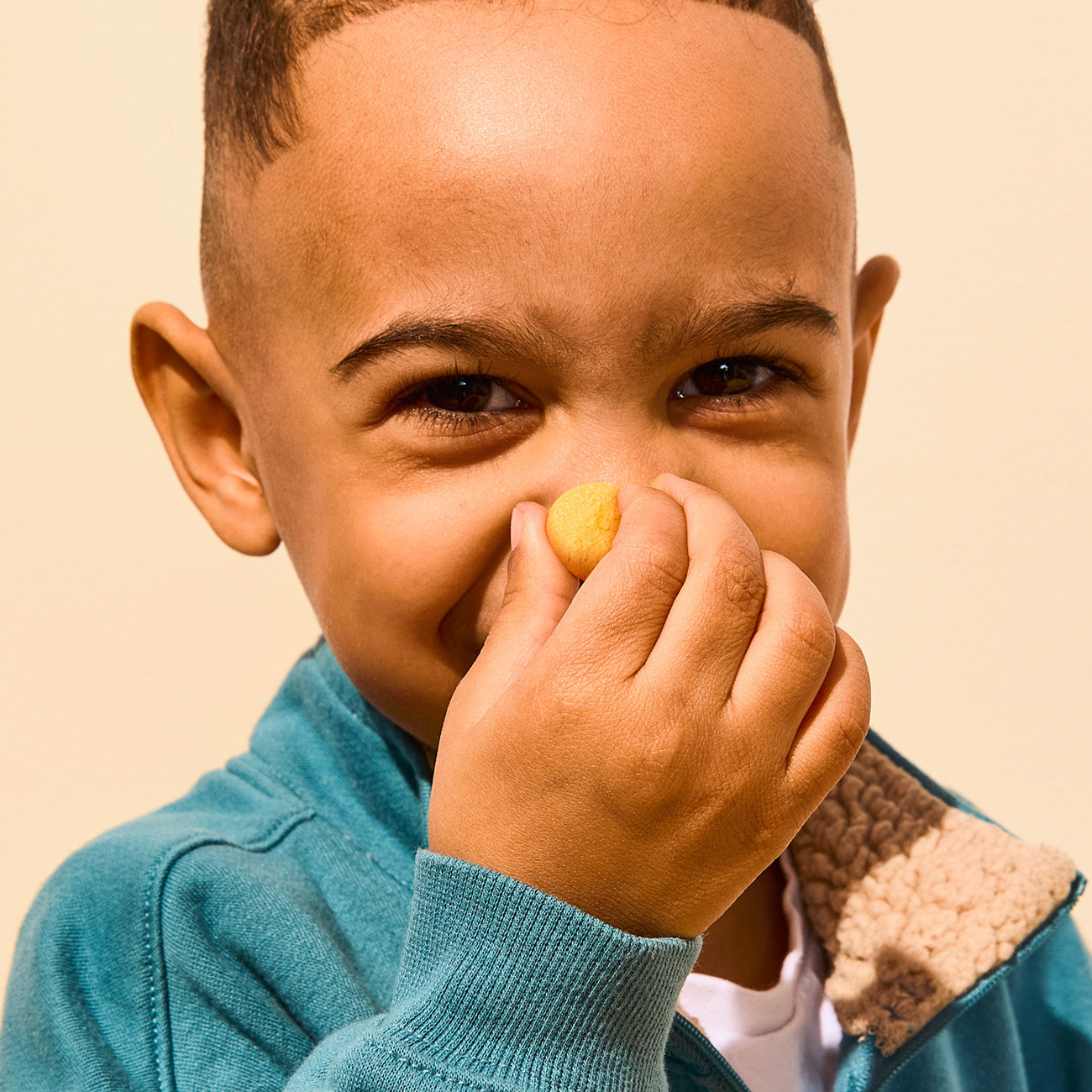 child holding a coconut smoothie melt in front of their nose